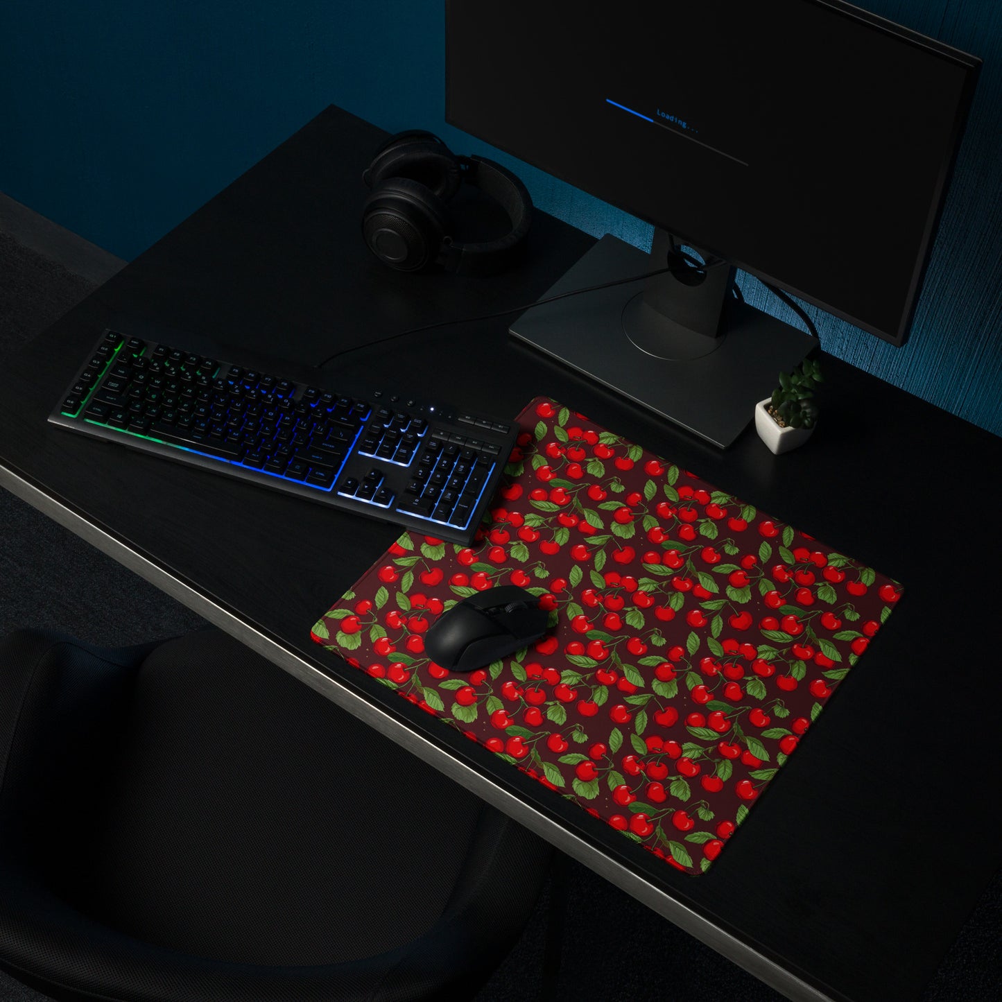 A 18" x 16" desk pad with cherries all over it shown on a desk setup. Red in color.