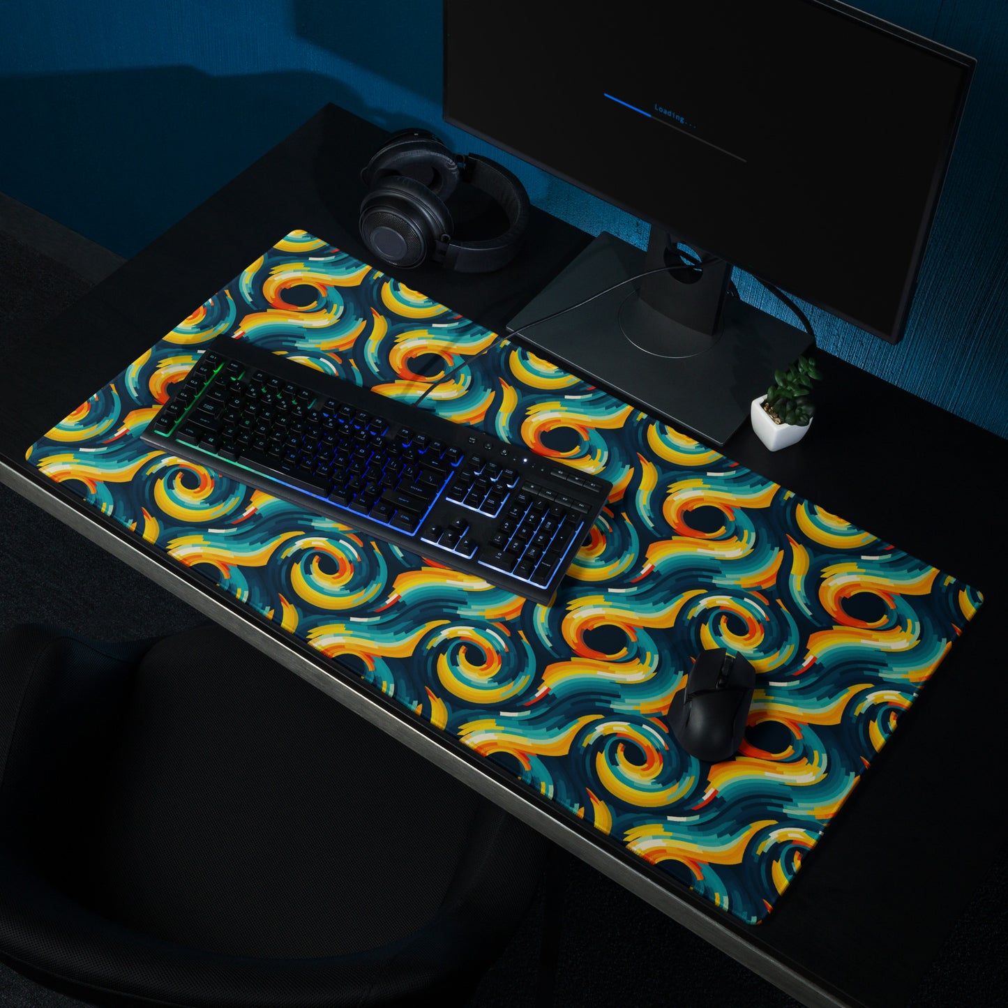 A 36" x 18" desk pad with swirls all over it shown on a desk setup. Yellow and Blue in color.