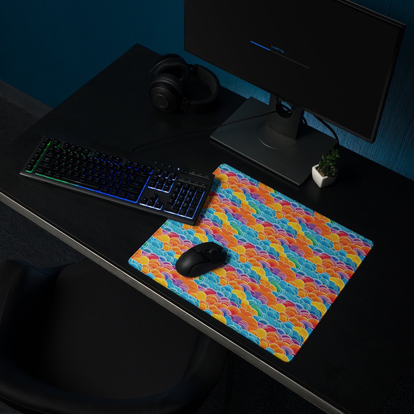 An 18" x 16" desk pad with bubbly swirly clouds all over it shown on a desk setup. Rainbow colored.