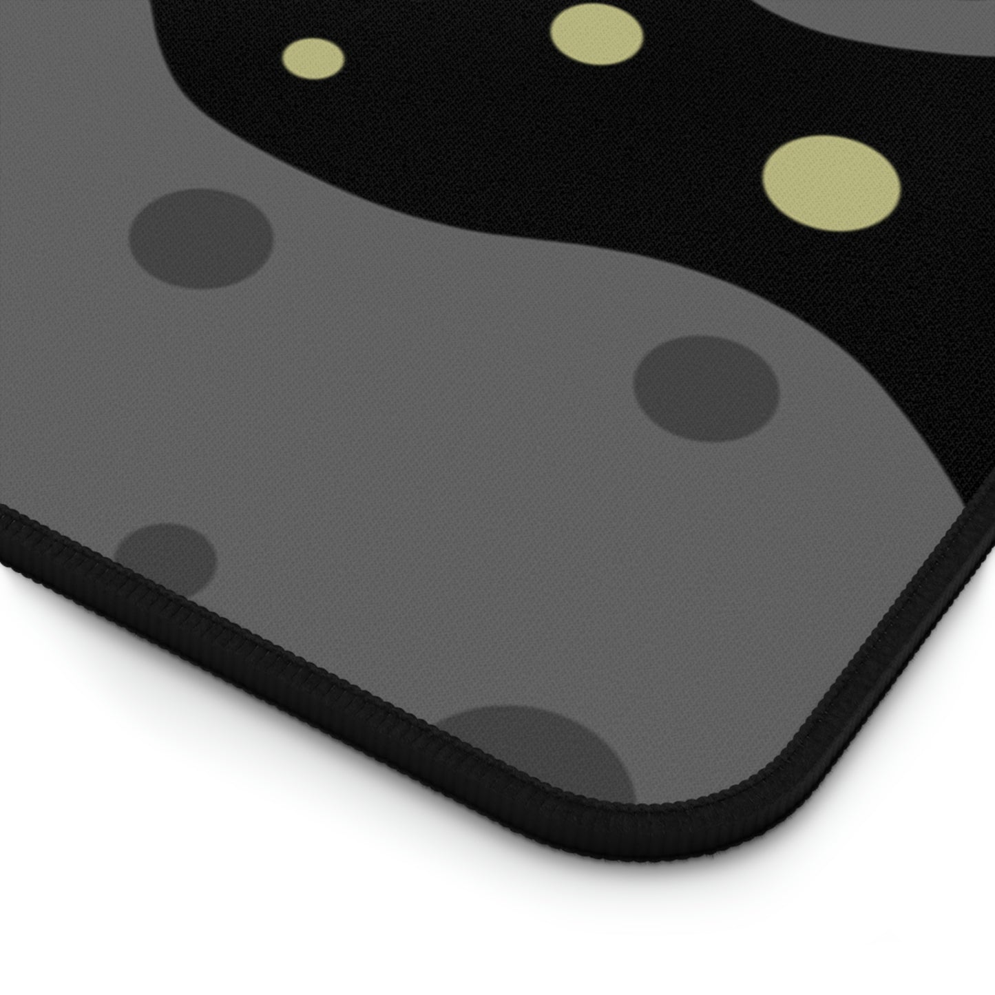 The corner of a 31" x 15.5" desk mat with a black background, gray asteroids, and yellow stars.