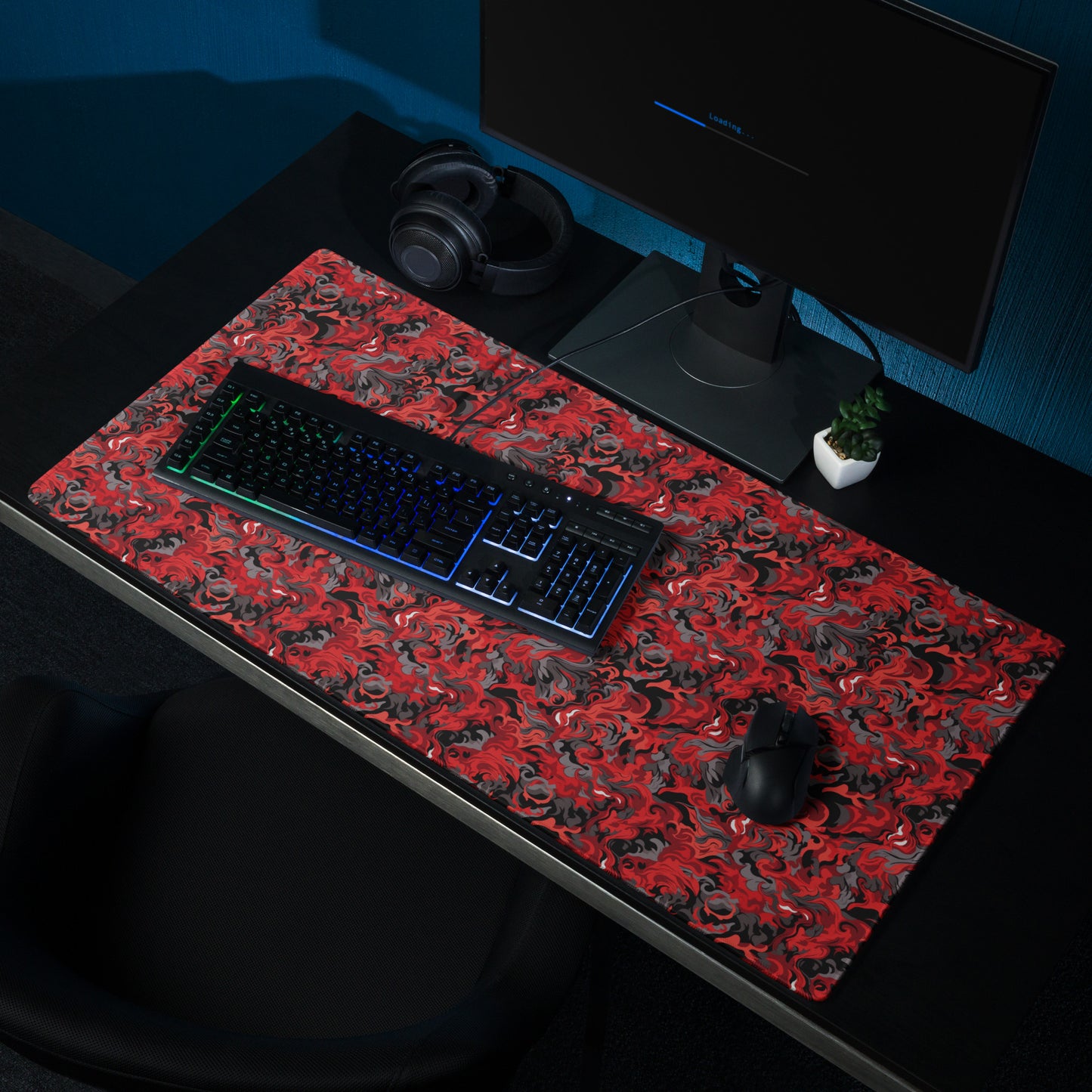 A 36" x 18" desk pad with a black and red camo pattern sitting on a desk.