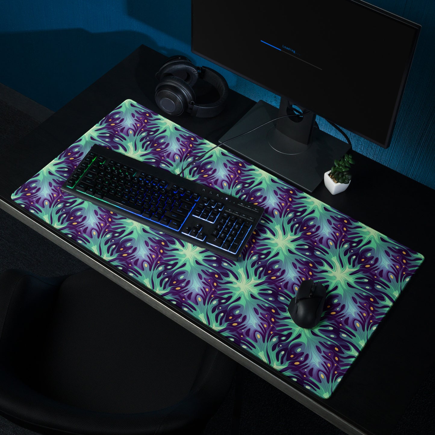 A 36" x 18" desk pad with a green and blue abstract pattern sitting on a desk.