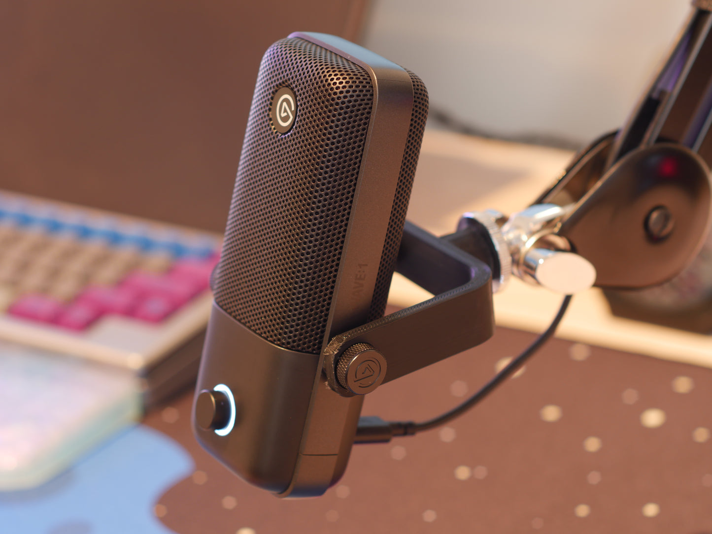 A black microphone mount attached to a boom arm and holding the Elgato Wave microphone.