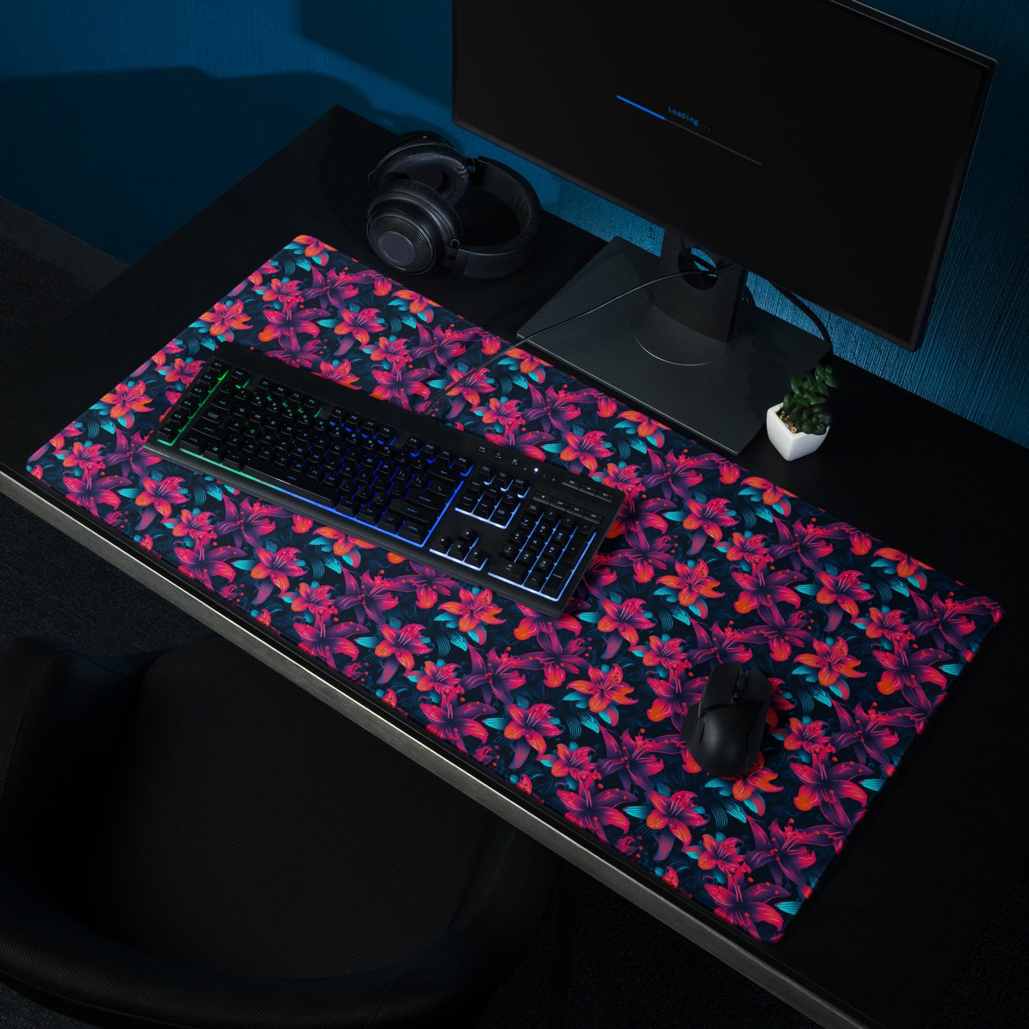 A 36" x 18" desk pad with a neon red and blue floral pattern sitting on a desk.