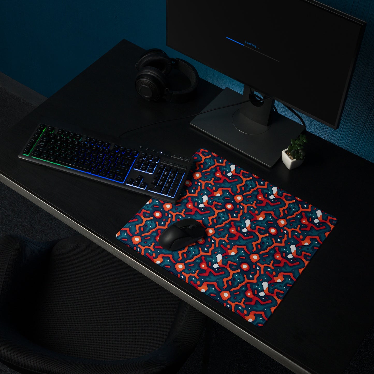 A 18" x 16" desk pad with a blue and orange crack pattern sitting on a desk.