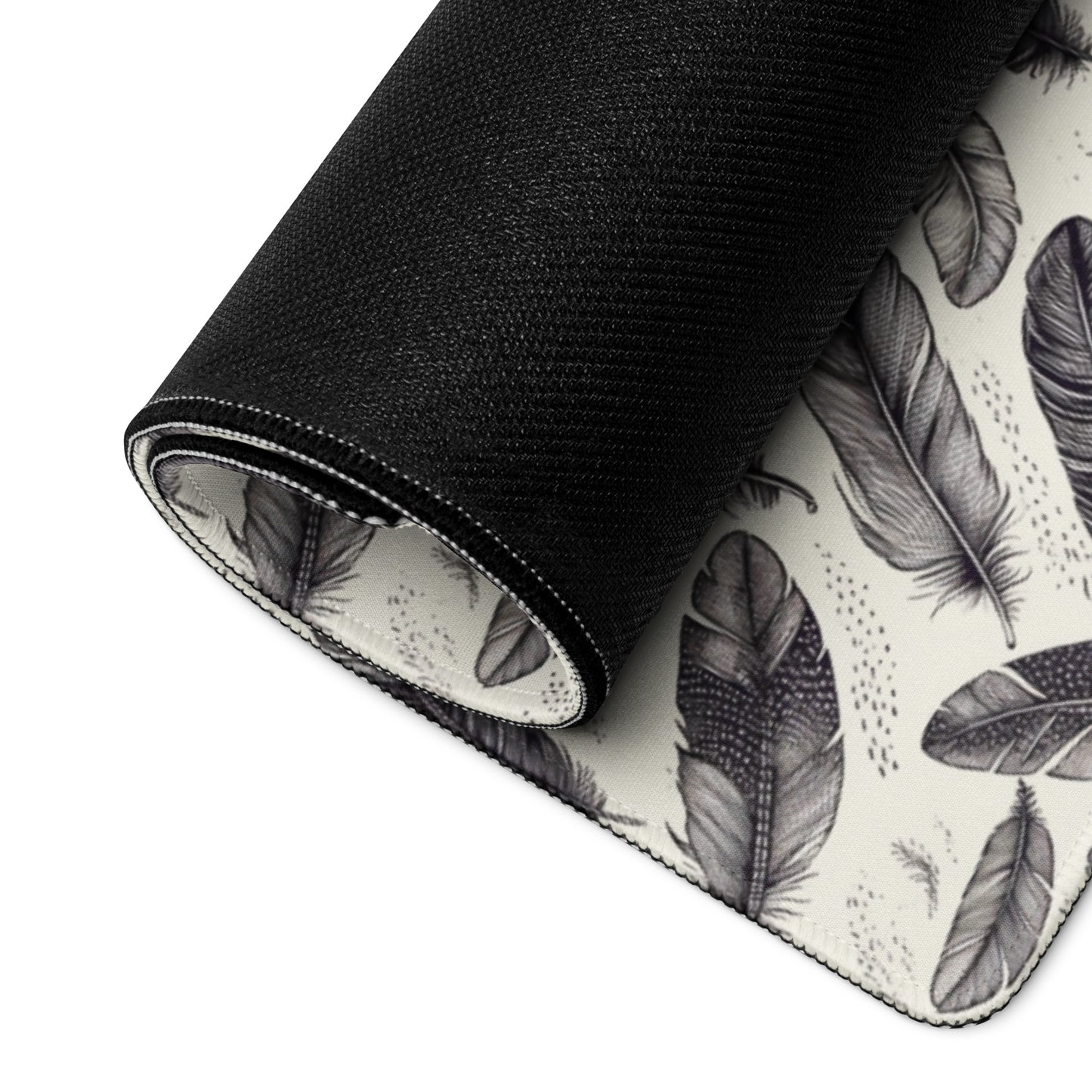 A 36" x 18" gaming desk pad with black and white feathers rolled up.