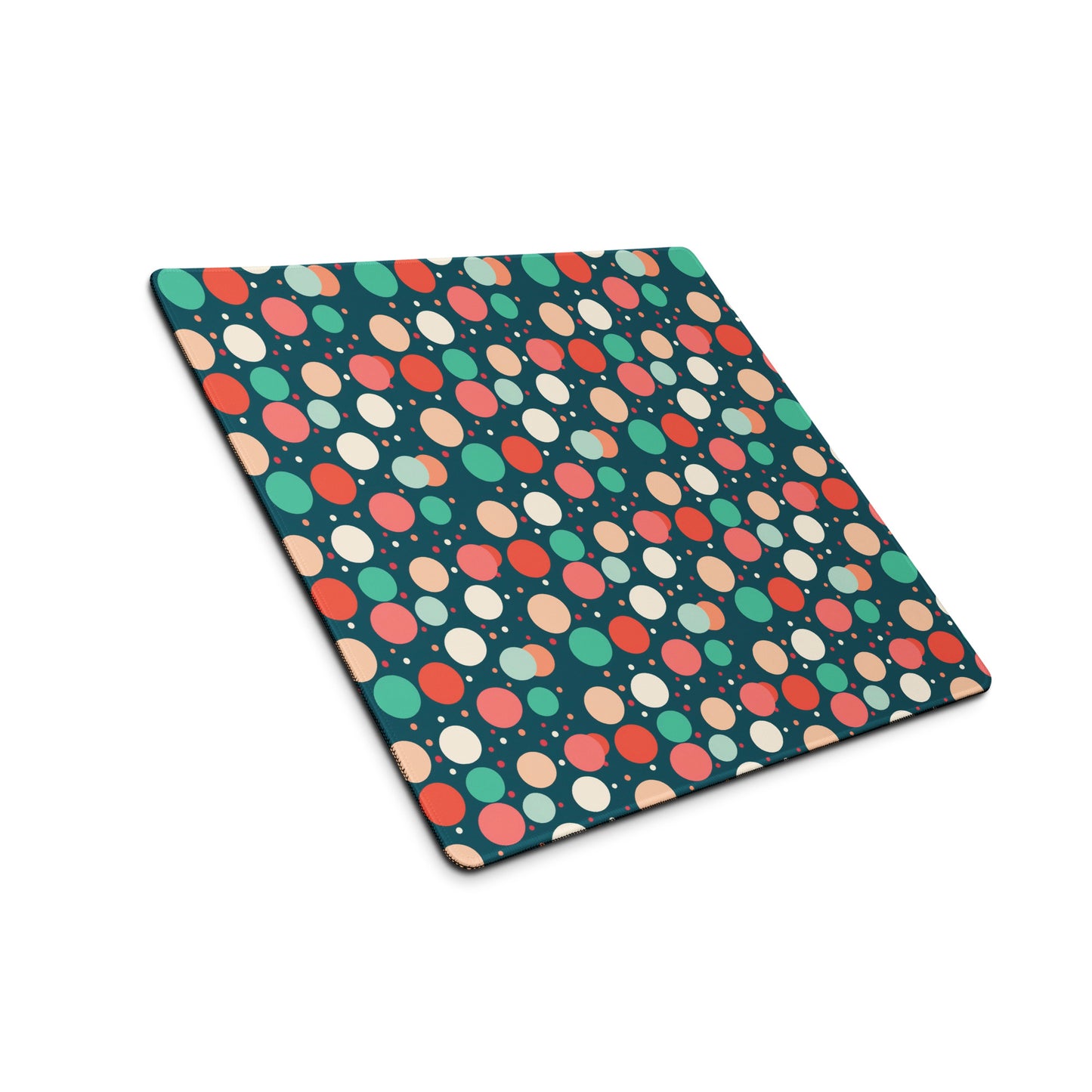 A 18" x 16" desk pad with red teal and yellow polka dot pattern sitting at an angle.