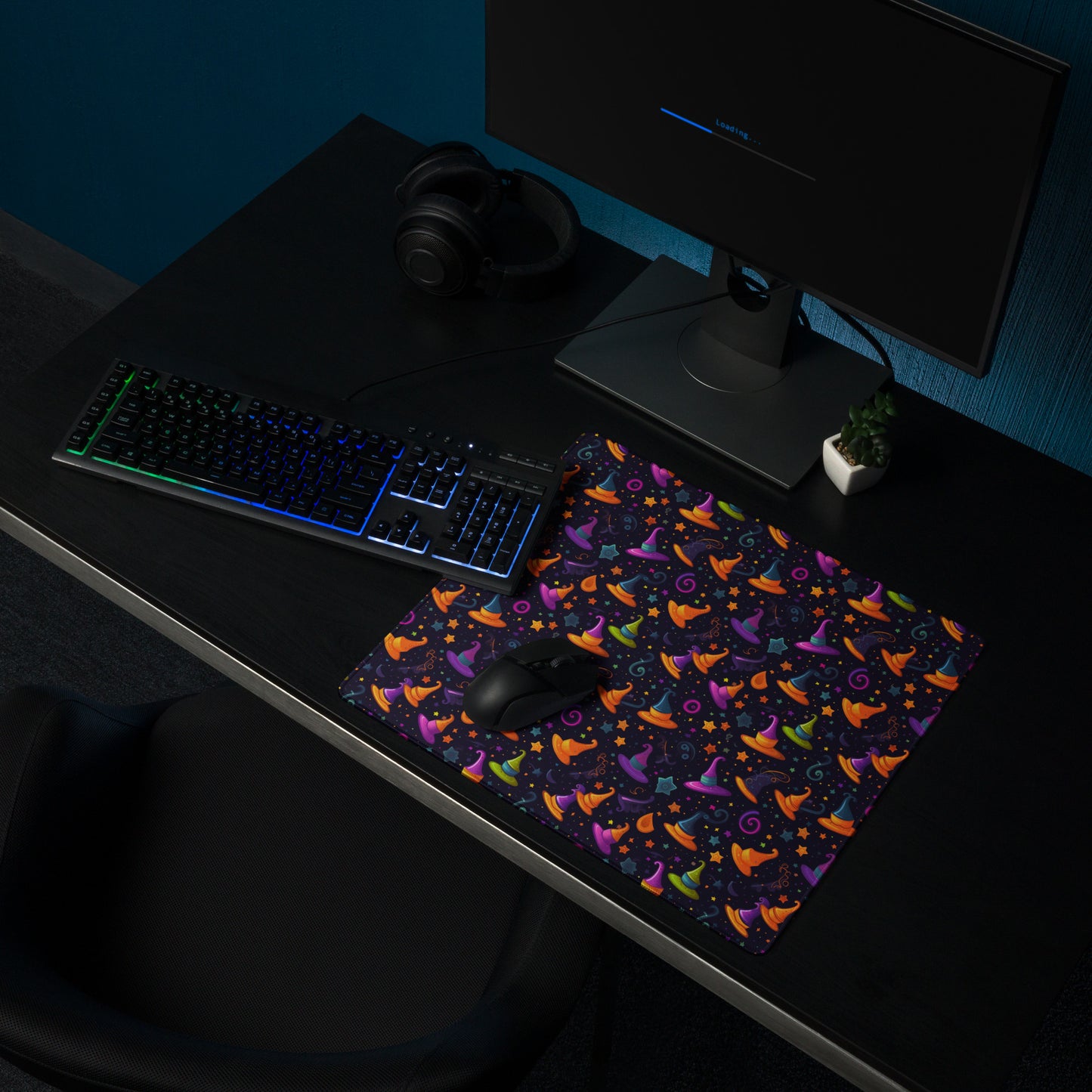A 18" x 16" desk pad with a orange and purple wizard hat pattern sitting on a desk,
