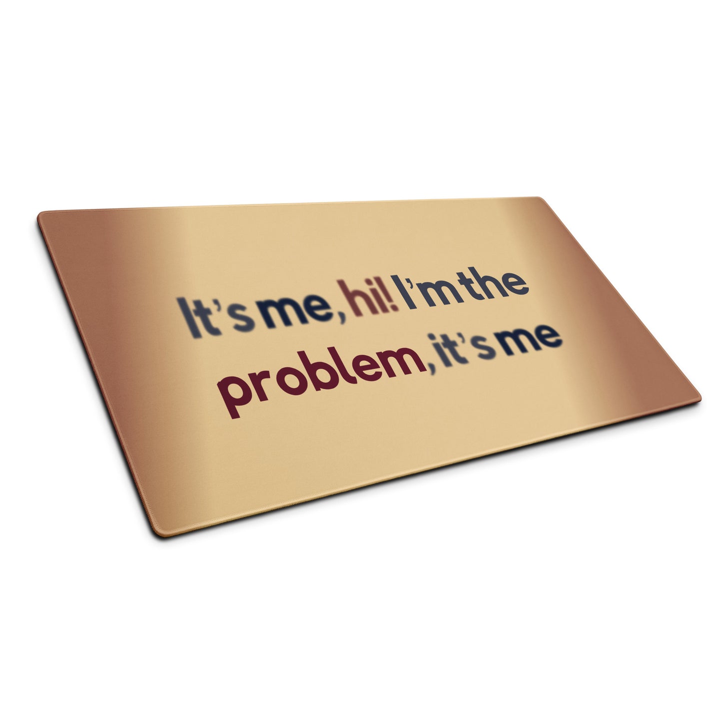 A beige gaming desk pad with the quote It's me, hi! I'm the problem, it's me. The desk pad sits at an angle.