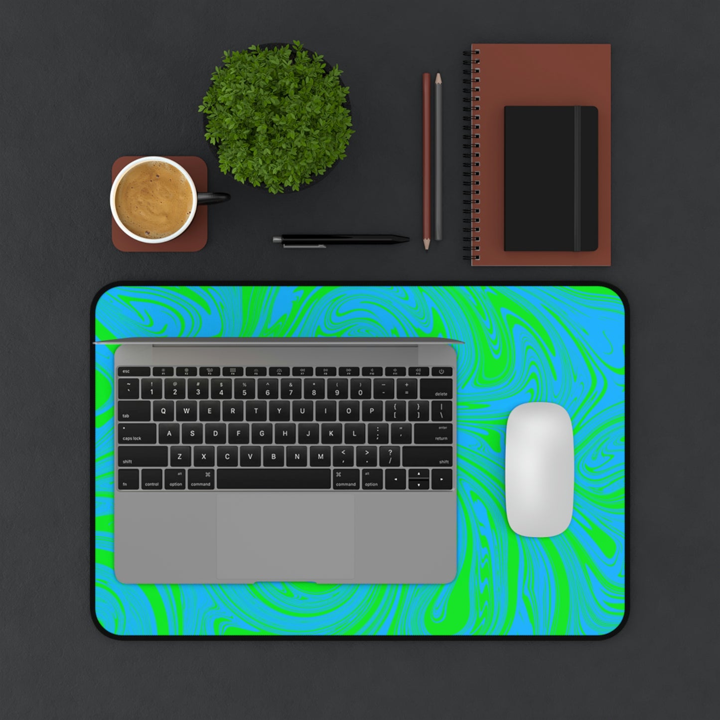 A 12" x 18" desk mat with blue and green swirls. A laptop and mouse sit on top of it.