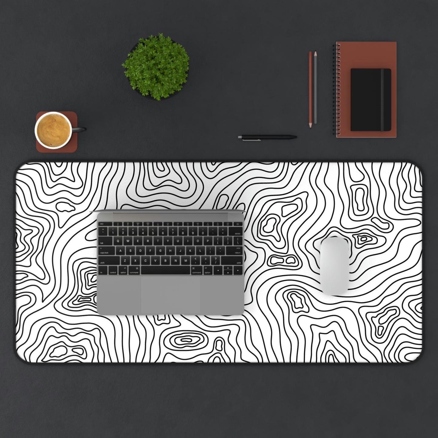 A 31" x 15.5" white desk mat with black topographic lines. A laptop and mouse sit on top of it.