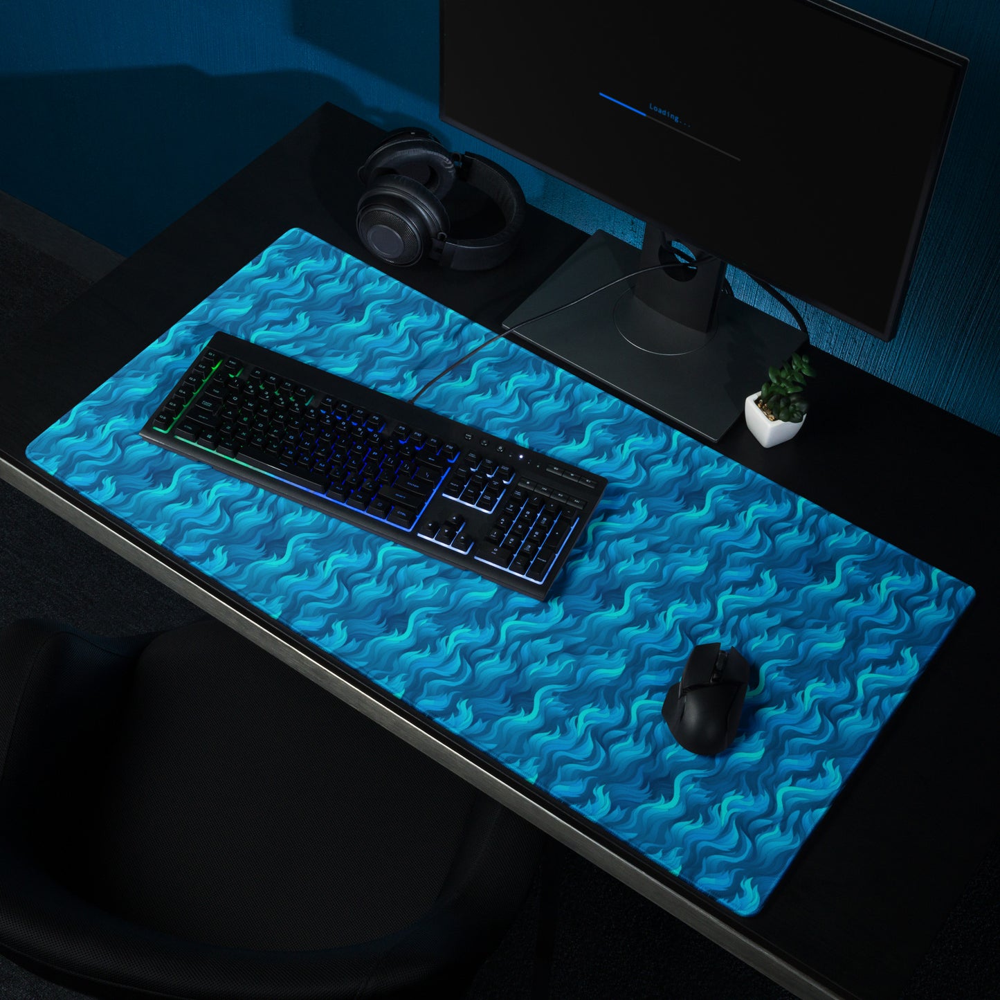A 36" x 18" desk pad with a wavy flame pattern on it shown on a desk. Blue in color.