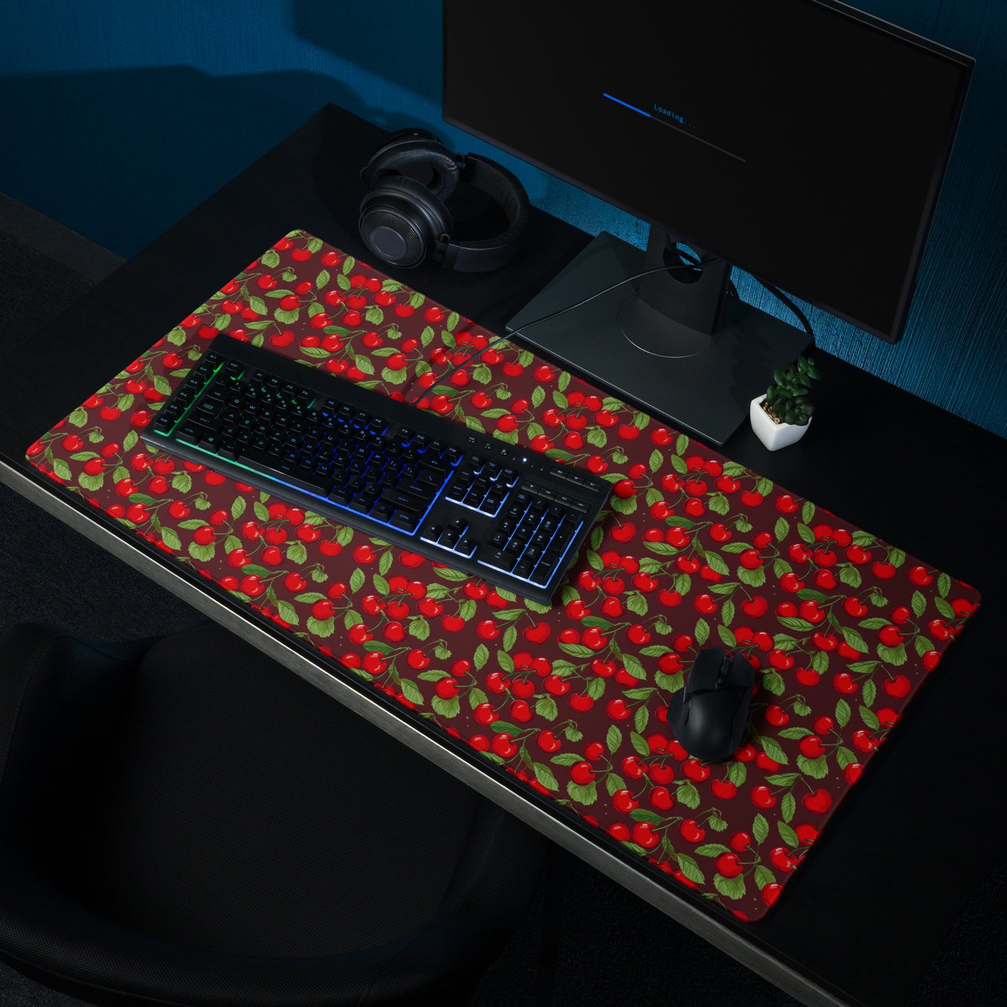 A 36" x 18" desk pad with cherries all over it shown at a desk. Red in color.