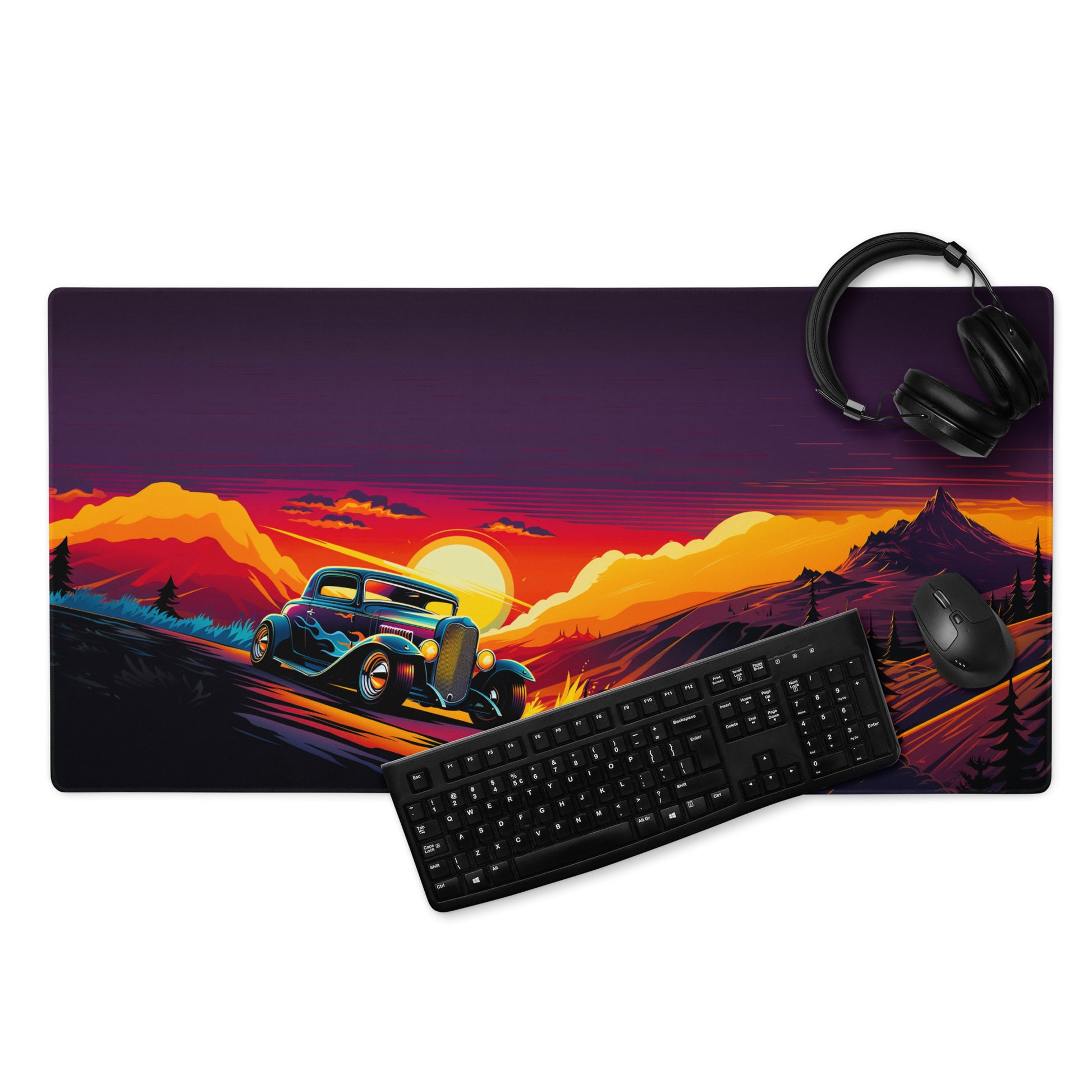 A 36" x 18" gaming desk pad with an old hot rod racing down a road with mountains in the background displayed with a keyboard, mouse and headphones. Purple and Orange in color. 