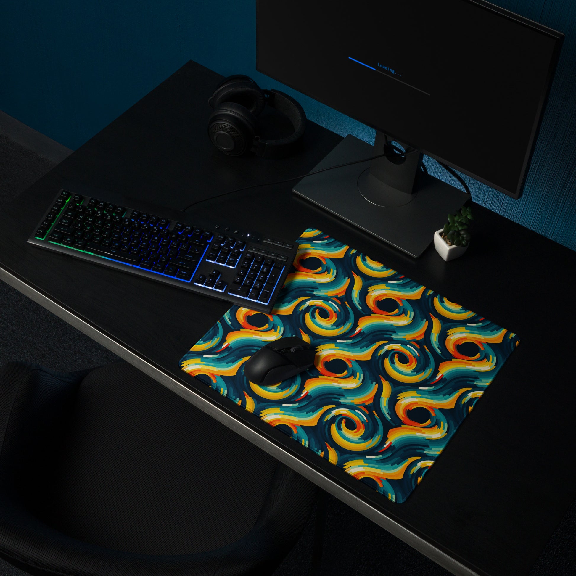 A 18" x 16" desk pad with swirls all over it shown on a desk setup. Yellow and Blue in color.