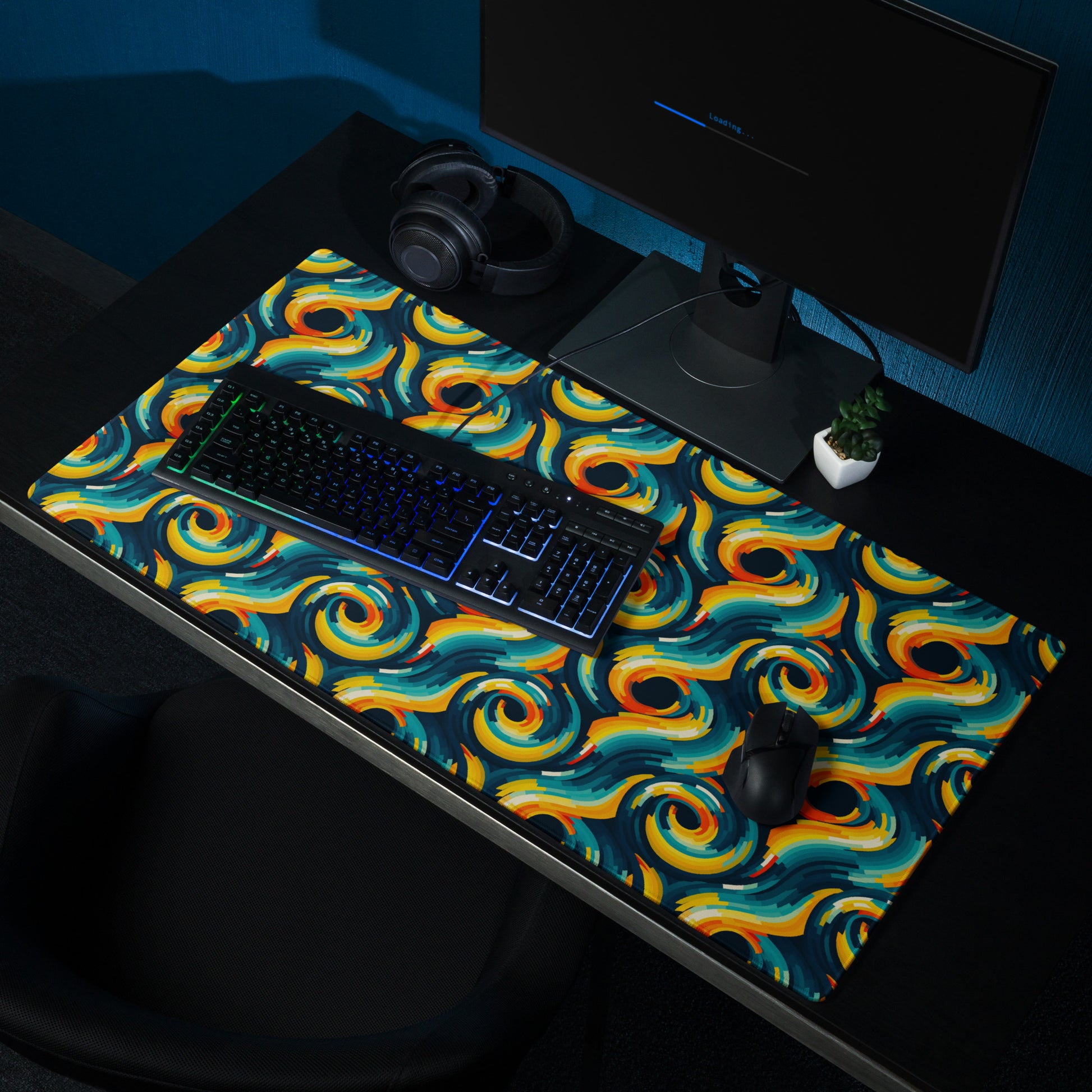  A 36" x 18" desk pad with swirls all over it shown on a desk setup. Yellow and Blue in color.
