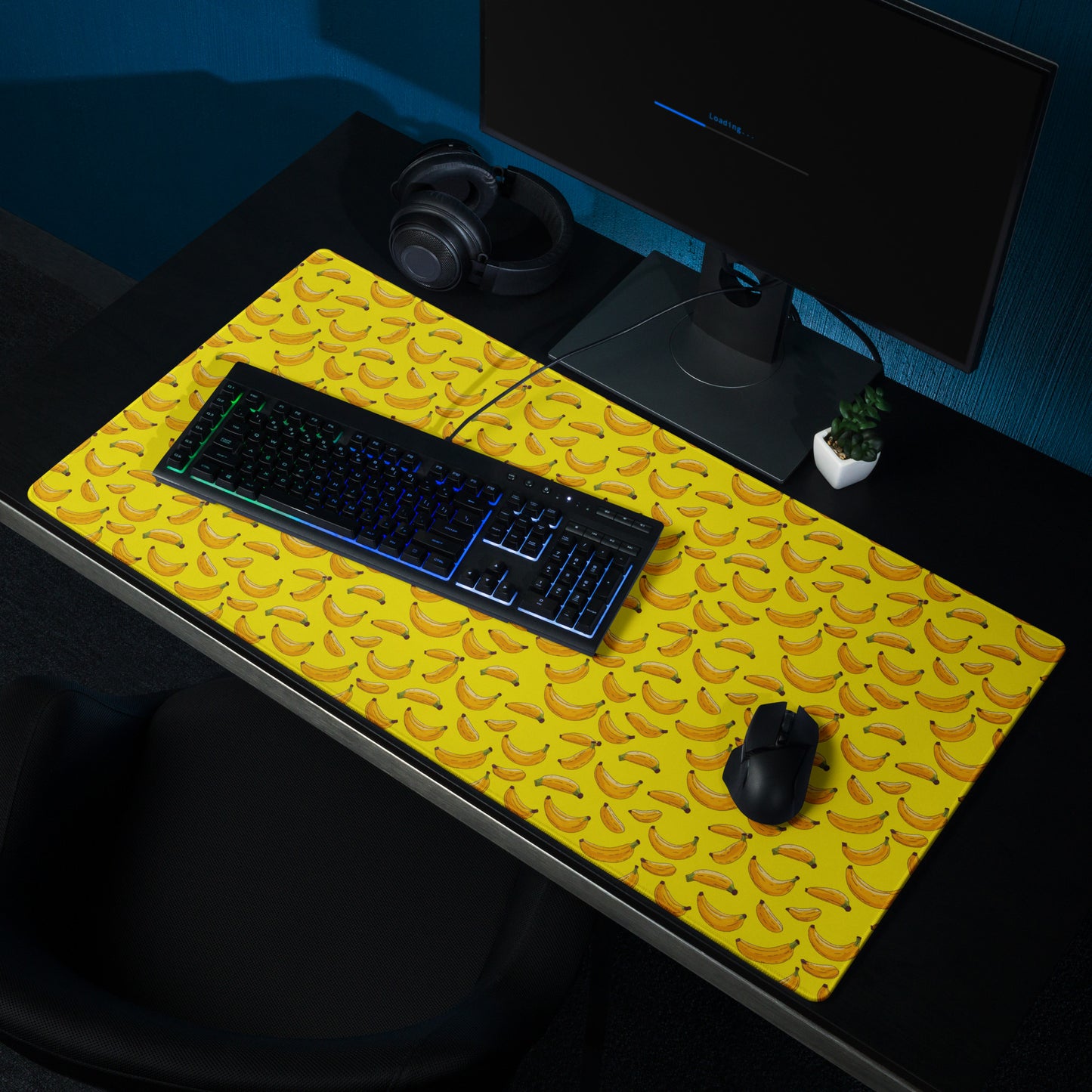 A 36" x 18" desk pad with bananas all over it shown on a desk setup. Yellow in color.