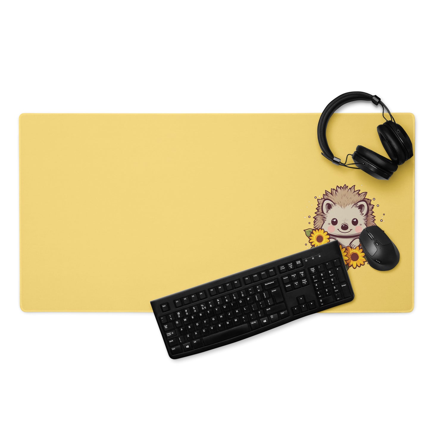A 36" x 18" desk pad with a cute hedgehog surrounded by sunflowers on it displayed with a keyboard, headphones and a mouse. Yellow in color.