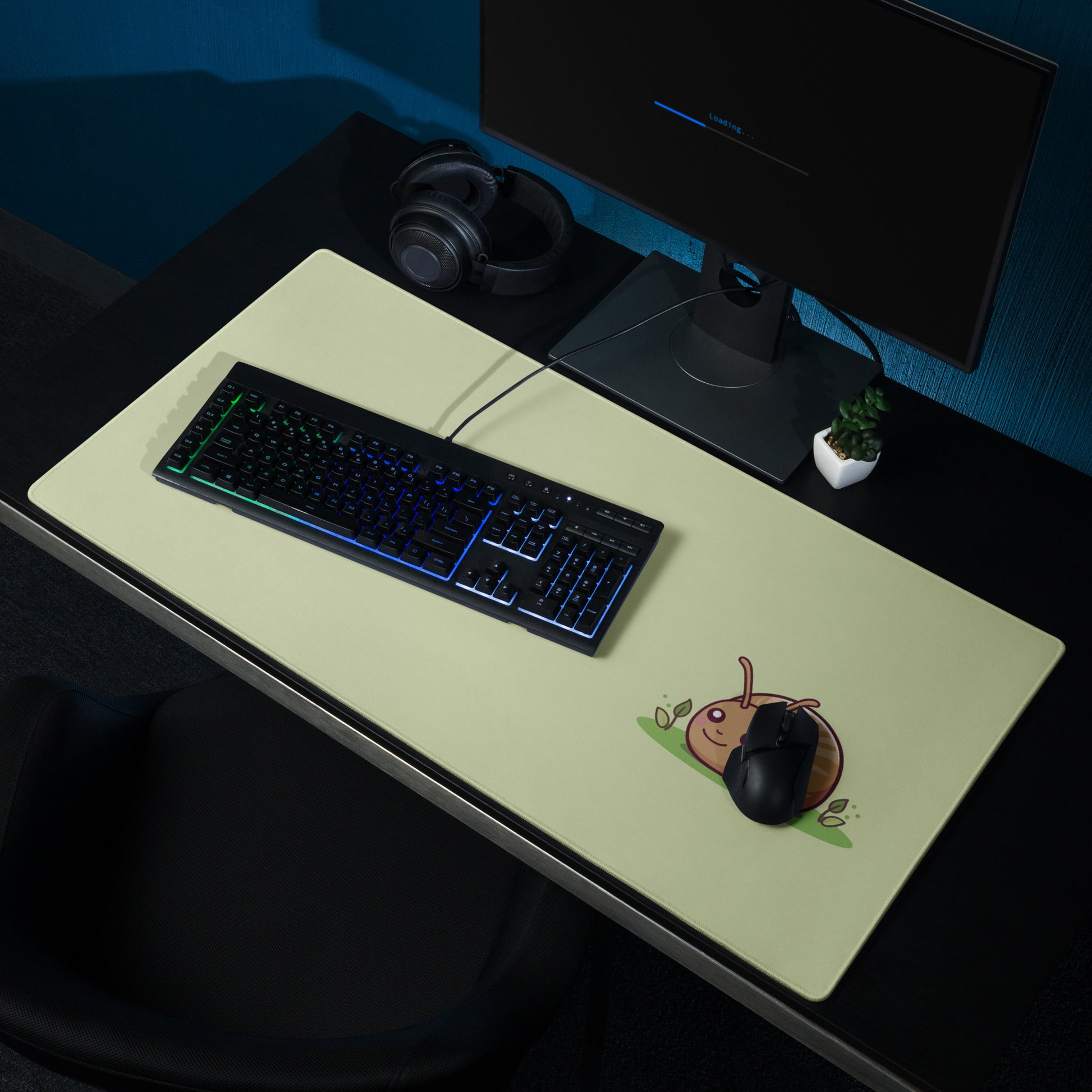 A 36" x 18" desk pad with a cute snail on it shown on a desk setup. Green in color.