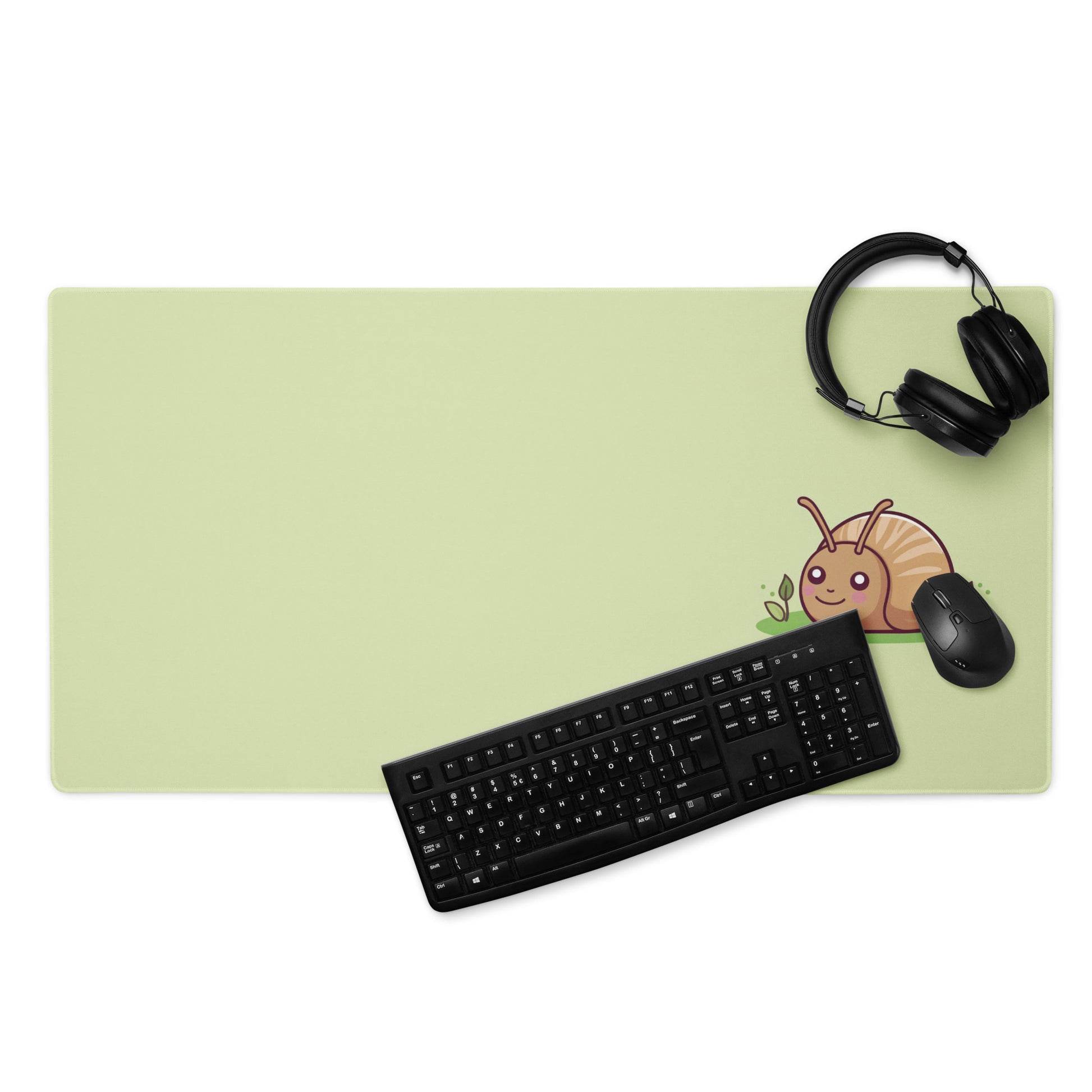 A 36" x 18" desk pad with a cute snail on it displayed with a keyboard, headphones and a mouse. Green in color.