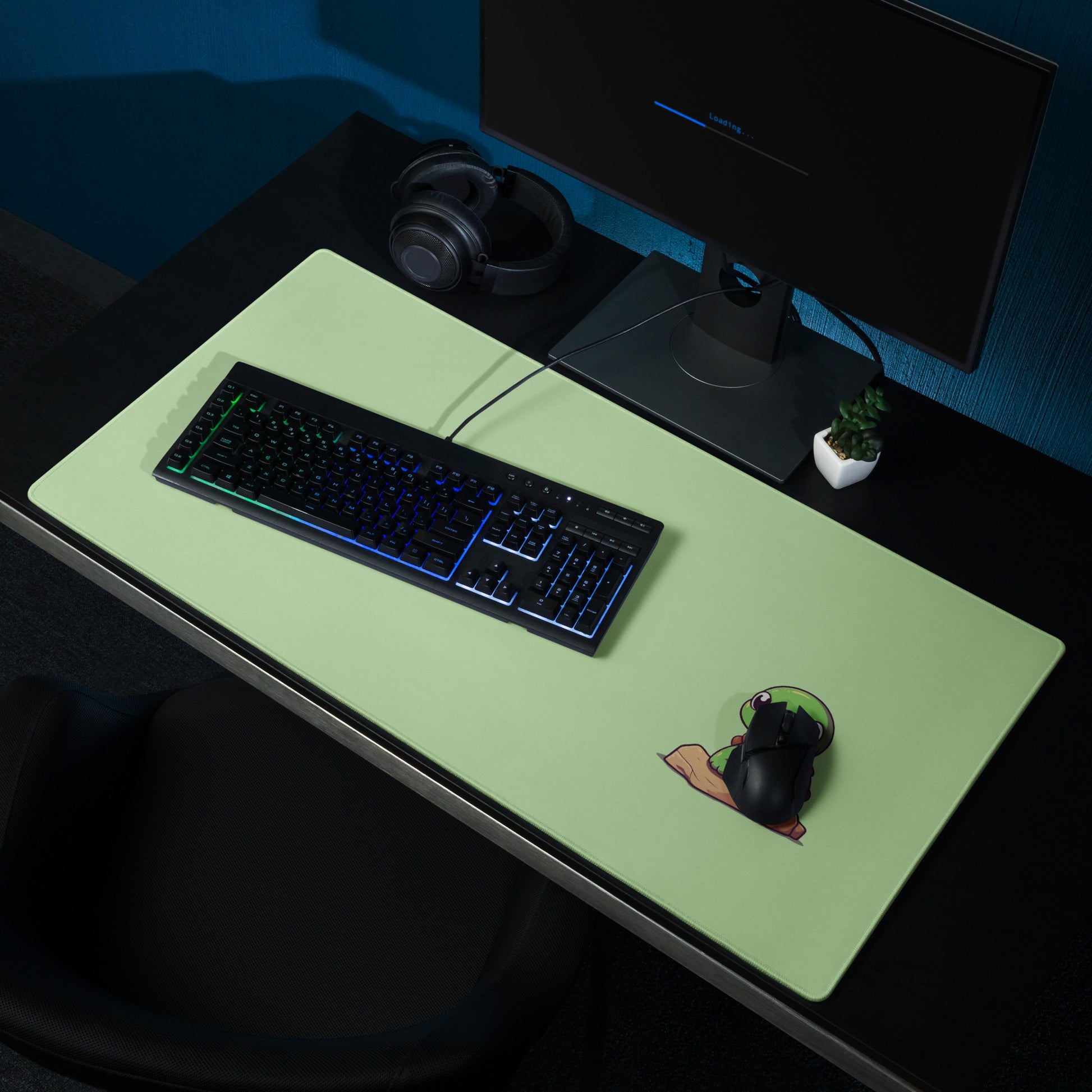 A 36" x 18" desk pad with a picture of a cute turtle sitting on a rock shown on a desk setup. Green in color.