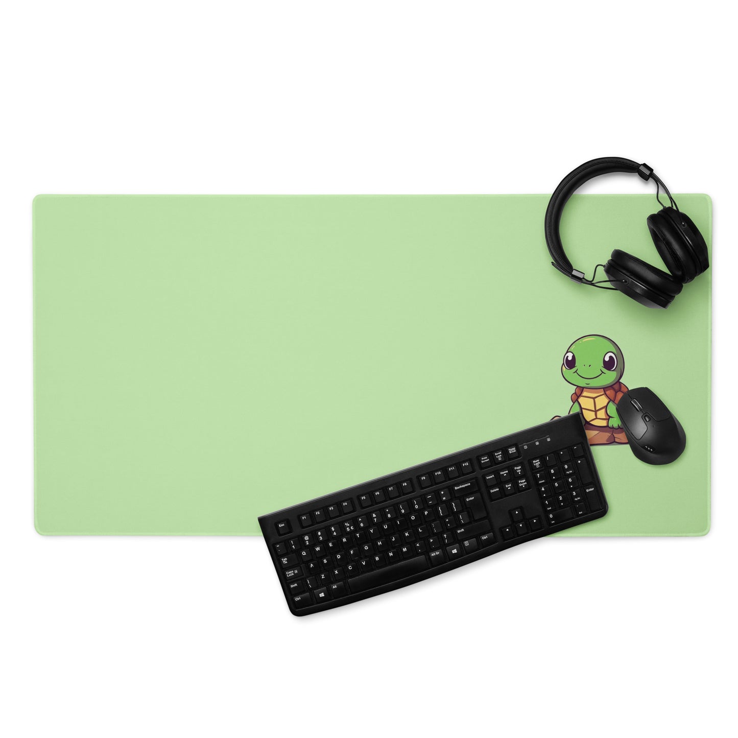 A 36" x 18" desk pad with a picture of a cute turtle sitting on a rock displayed with headphones, a keyboard and a mouse. Green in color.