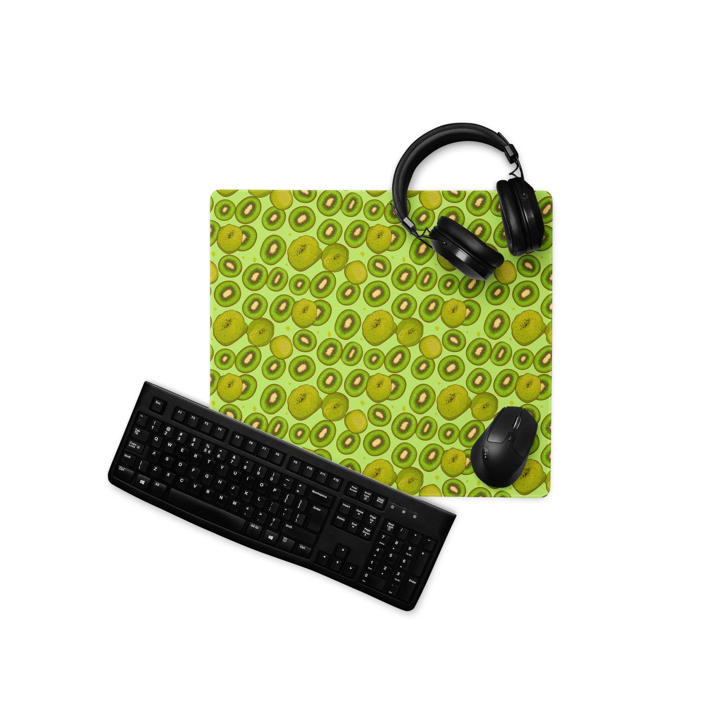 A 18" x 16" desk pad with Kiwis all over it displayed with a keyboard, headphones and a mouse on it. Green in color.