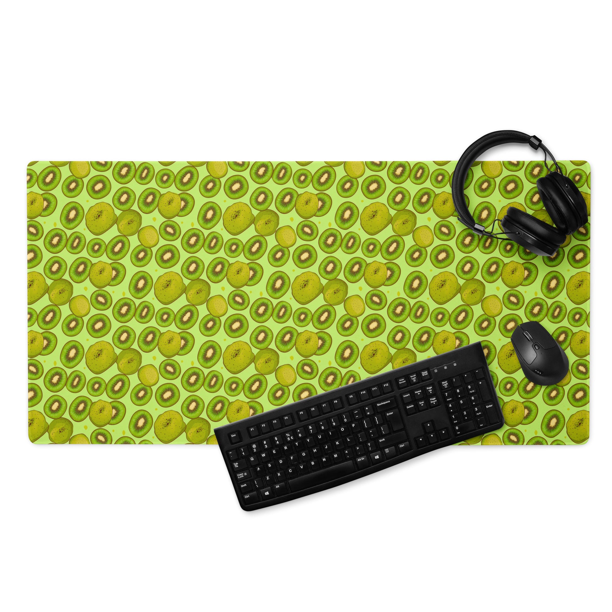 A 36" x 18" desk pad with Kiwis all over it displayed with a keyboard, headphones and a mouse. Green in color.