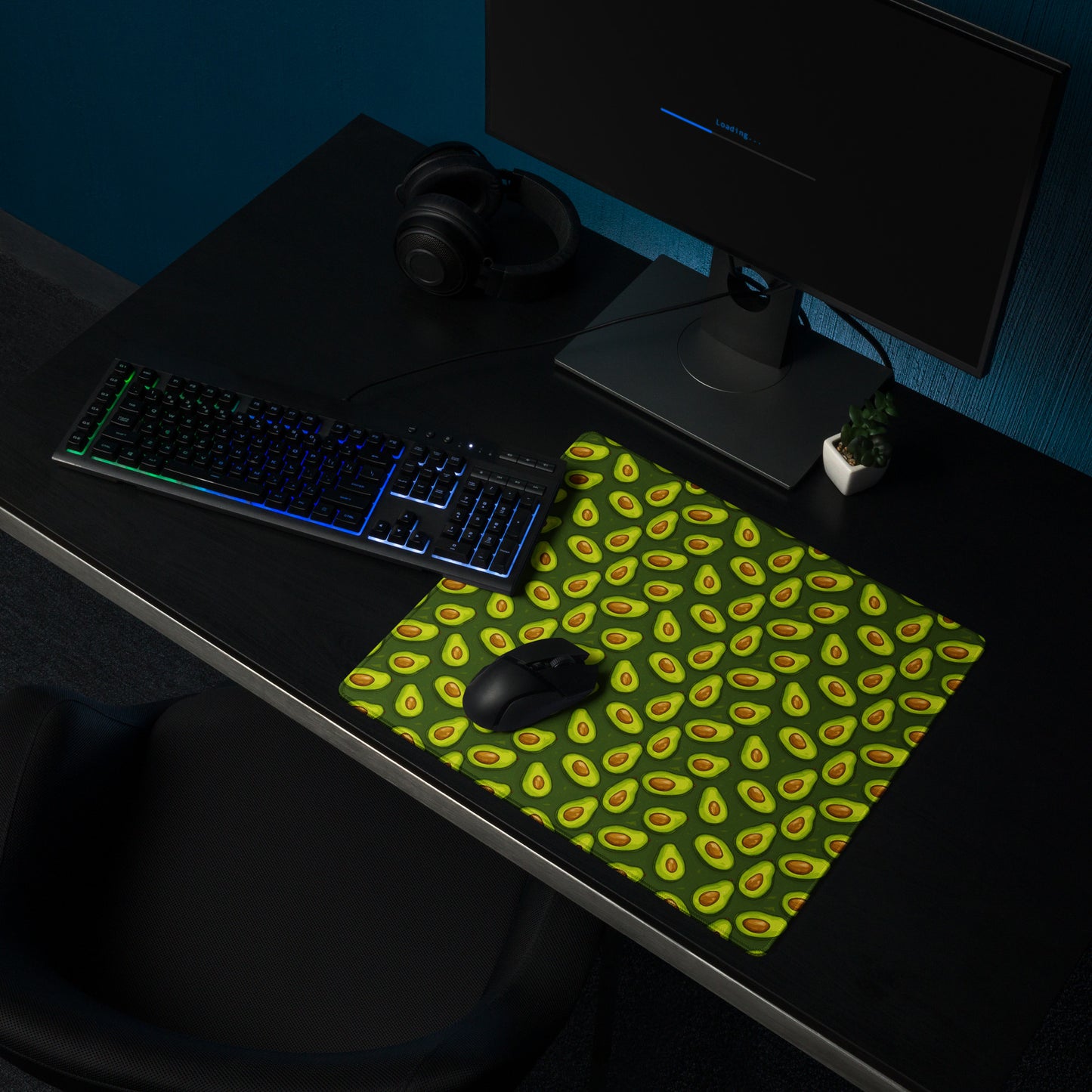 A 18" x 16" desk pad with lots of avocados on it shown on a desk setup. Green in color.