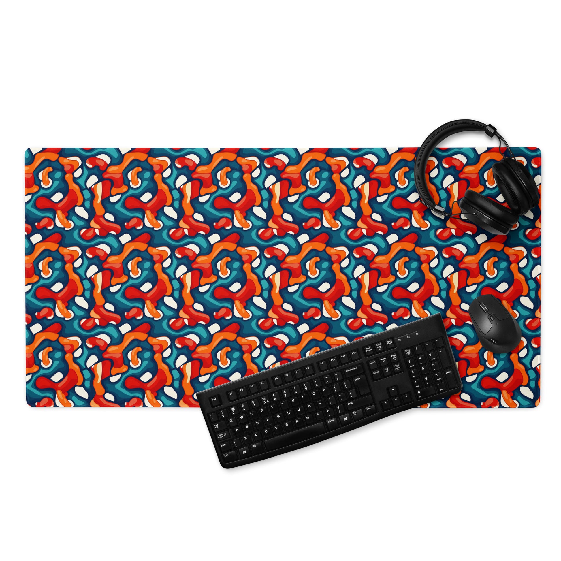 A 36" x 18" desk pad with abstract line art on it displayed with a keyboard, headphones and a mouse. Red, Teal and Orange in color.