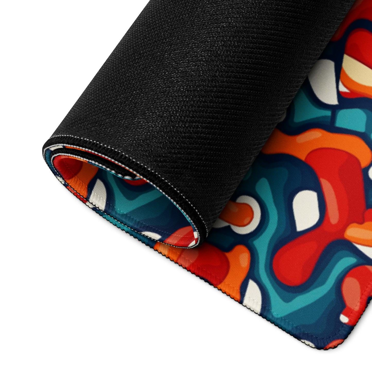 A 36" x 18" desk pad with abstract line art on it rolled up. Red, Teal and Orange in color.