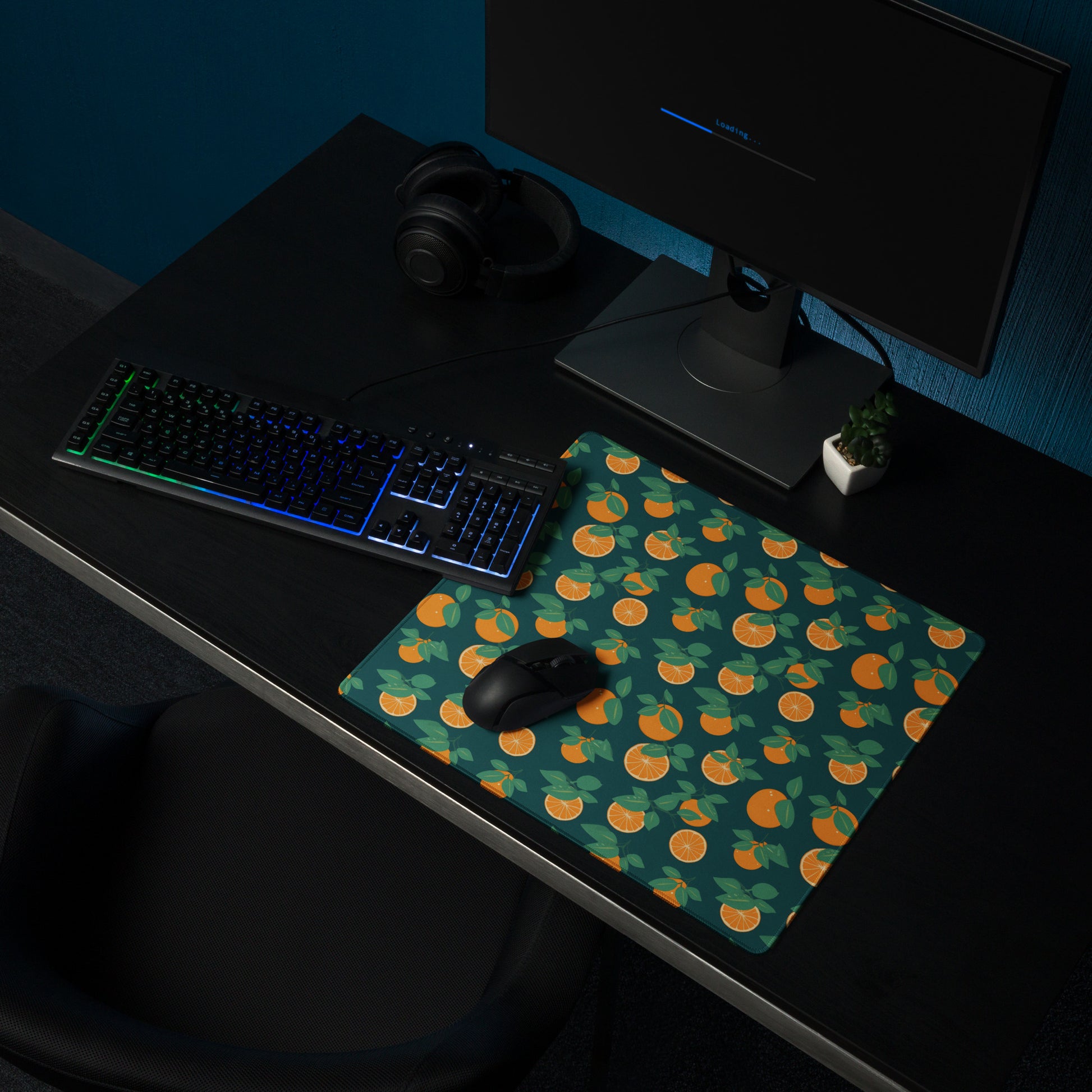 A 18" x 16" desk pad with oranges all over it shown on a desk setup. Orange and Blue in color.