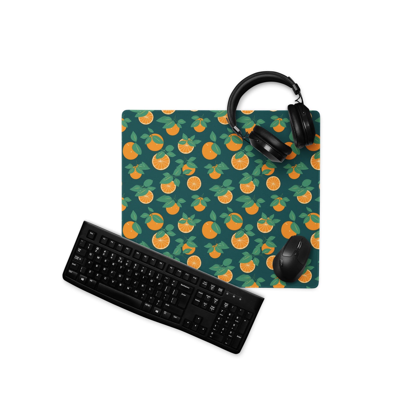 A 18" x 16" desk pad with oranges all over it displayed with a keyboard, headphones and a mouse. Orange and Blue in color.