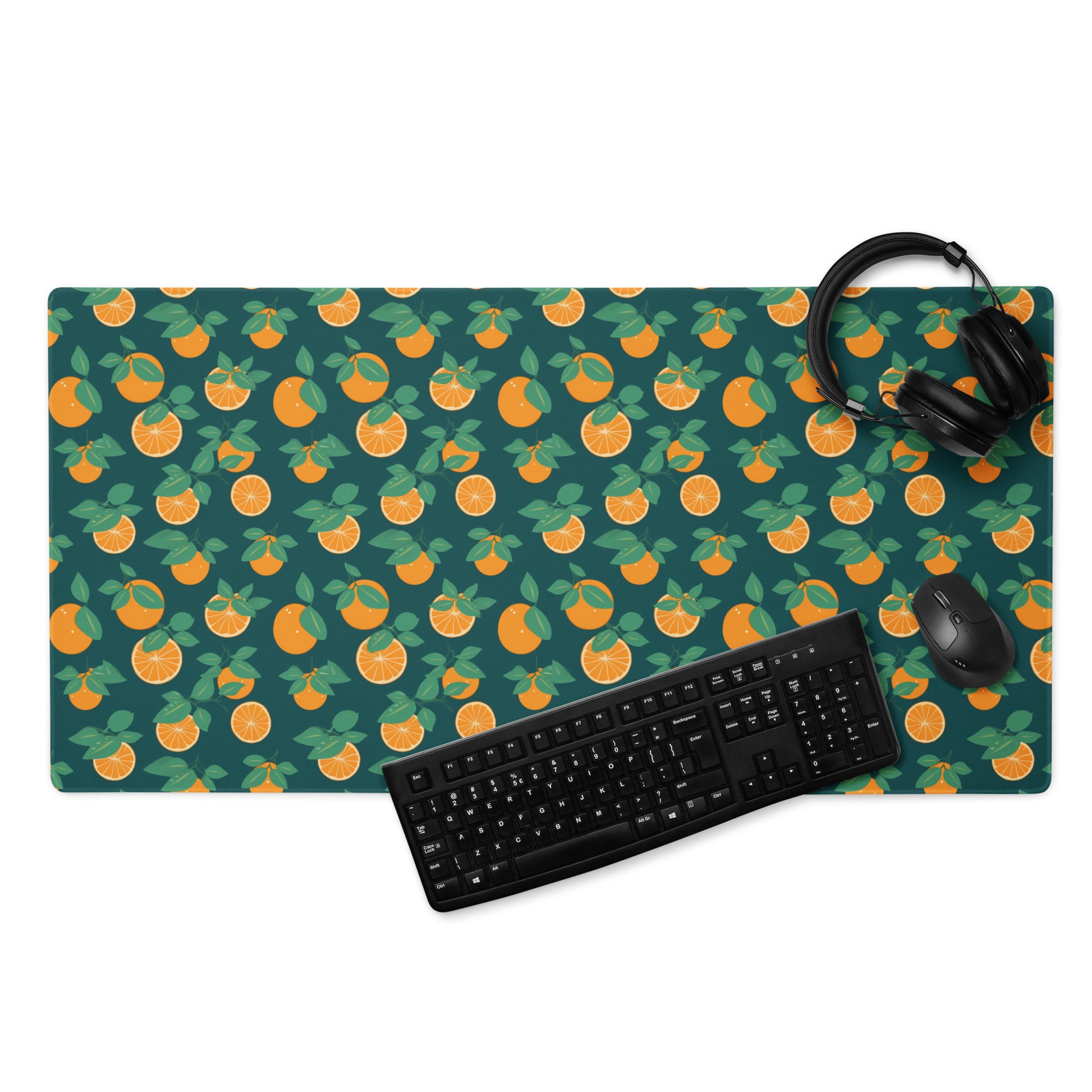 A 36" x 18" desk pad with oranges all over it displayed with a keyboard, headphones and a mouse. Orange and Blue in color.