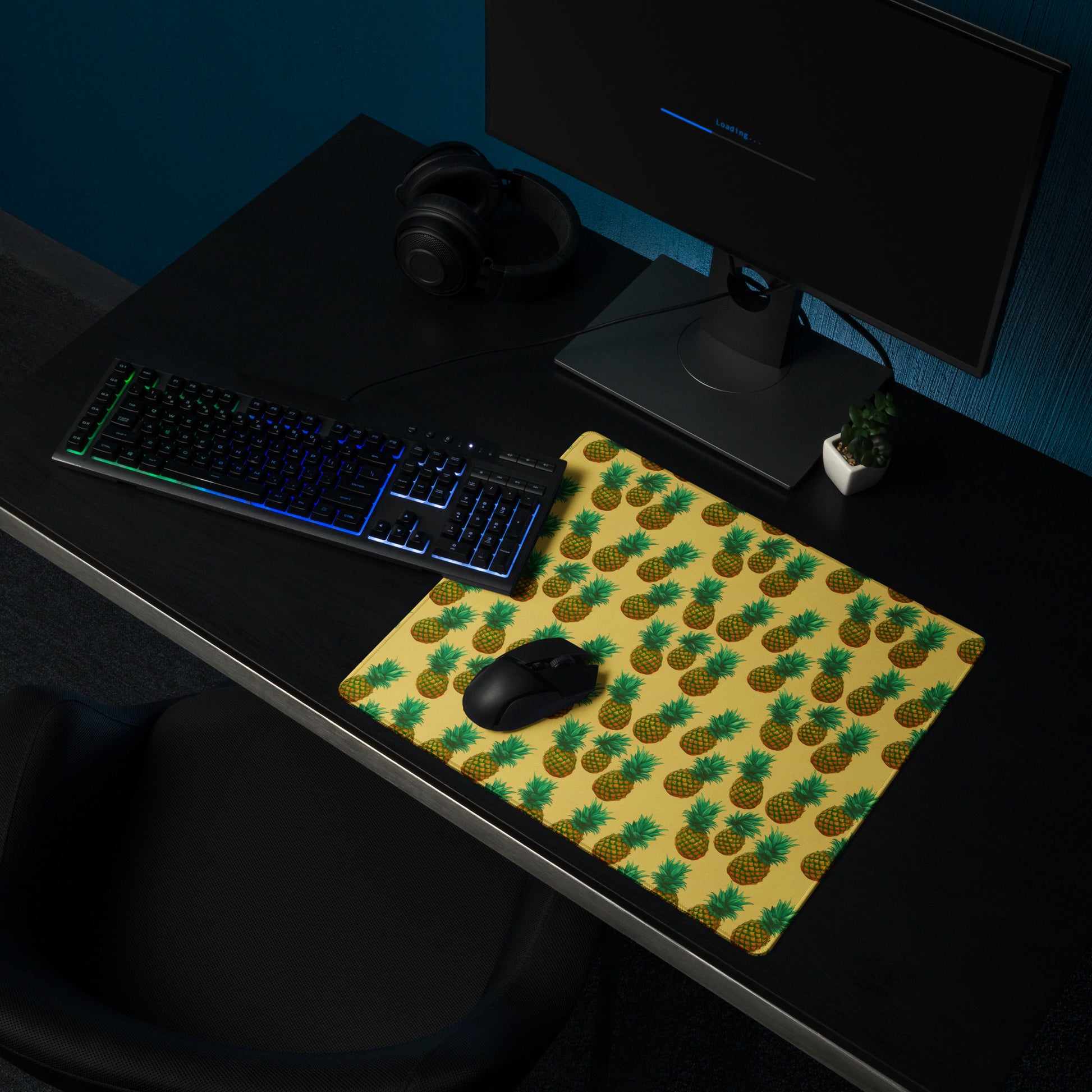 A 18" x 16" desk pad with pineapples all over it shown on a desk setup. Yellow in color.