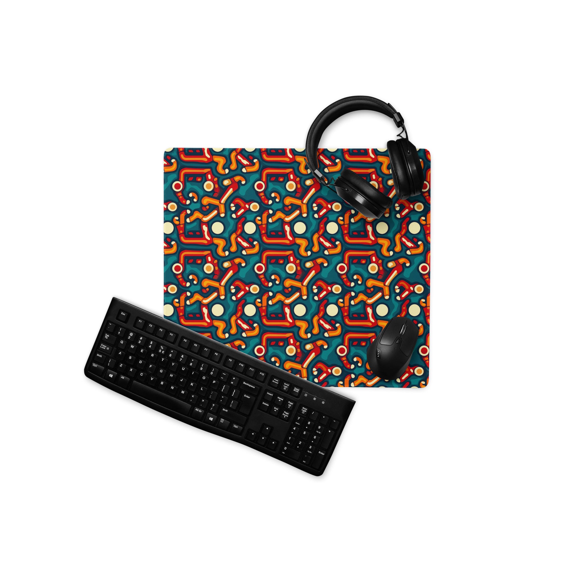 A 18" x 16" desk pad with abstract line art on it displayed with a keyboard, headphones and a mouse. Red, Orange and Teal in color.