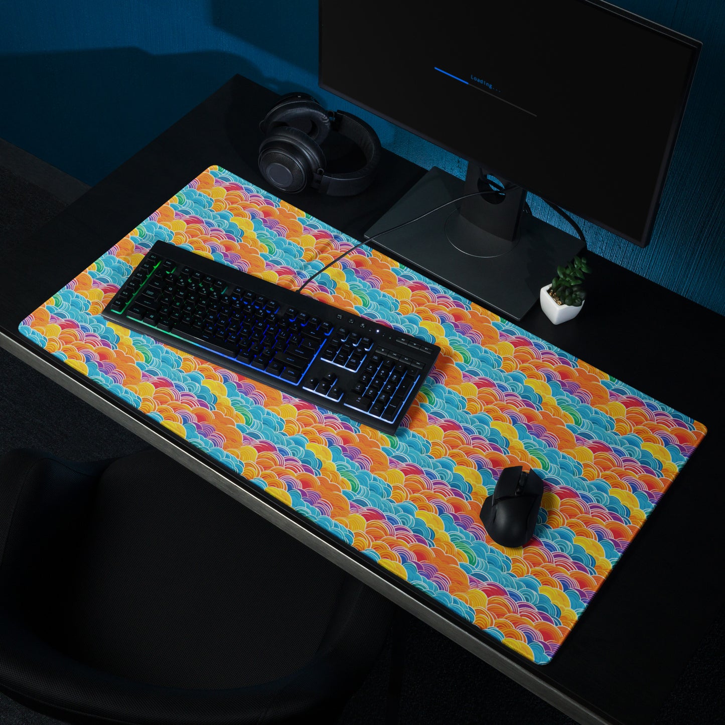 A 36" x 18" desk pad with bubbly swirly clouds all over it shown on a desk setup. Rainbow colored.