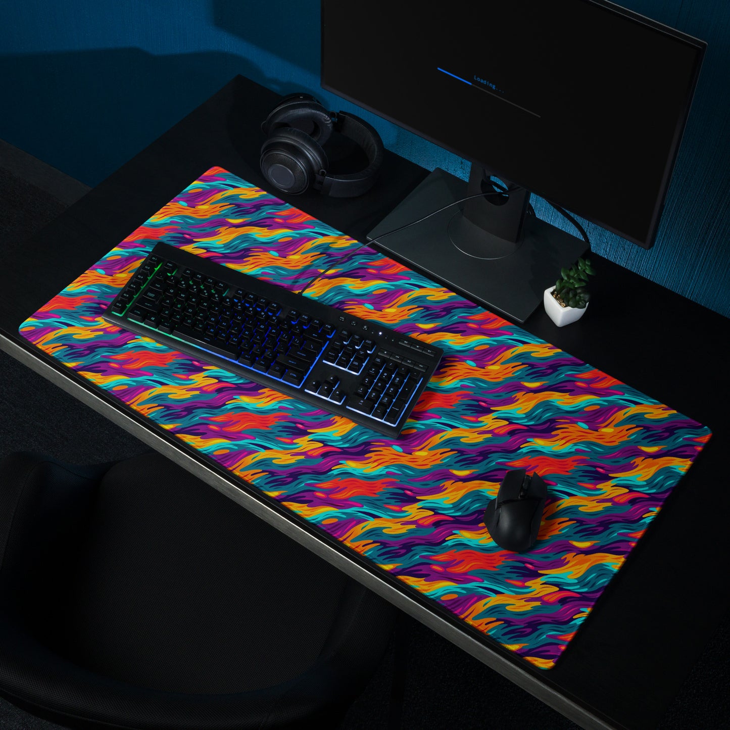 A 36" x 18" desk pad with a wavy flame pattern on it shown on a desk setup. Rainbow in color.