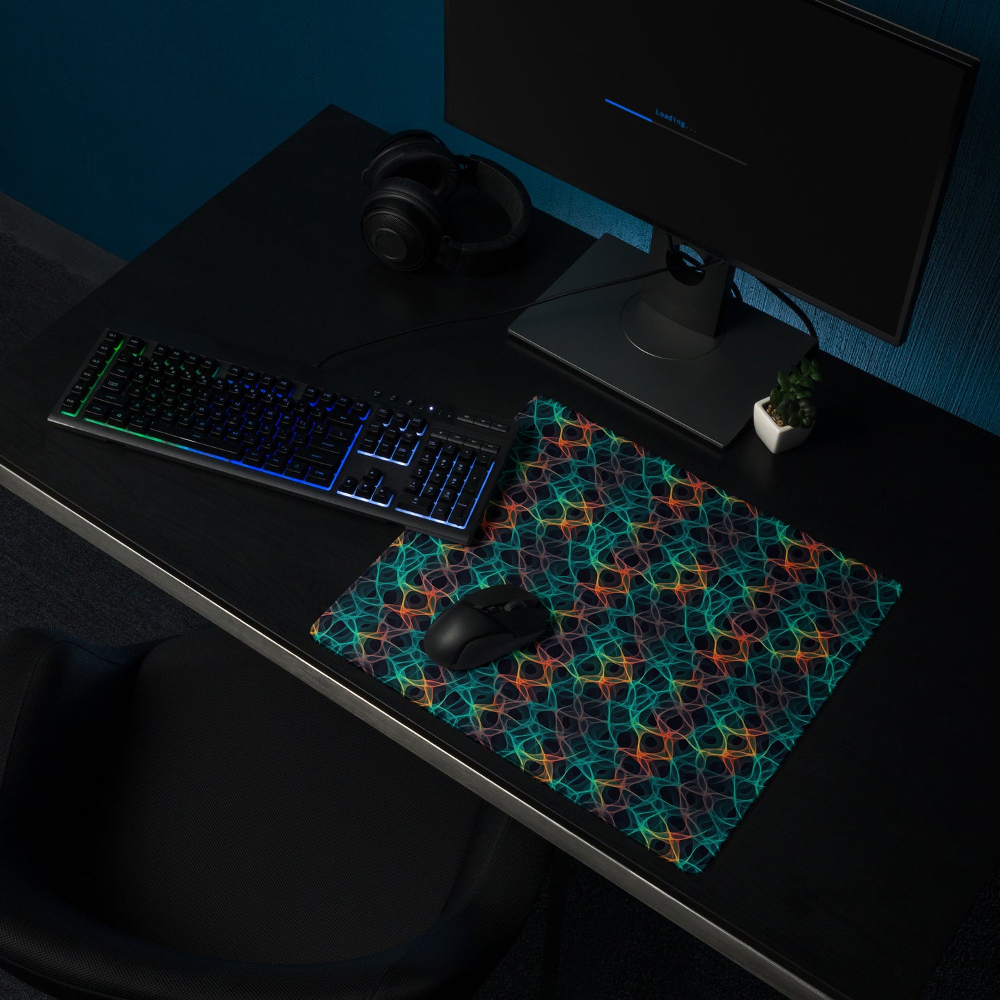 A 18" x 16" desk pad with an abstract pattern resembling a cell structure on it shown on a desk setup. Rainbow in color.