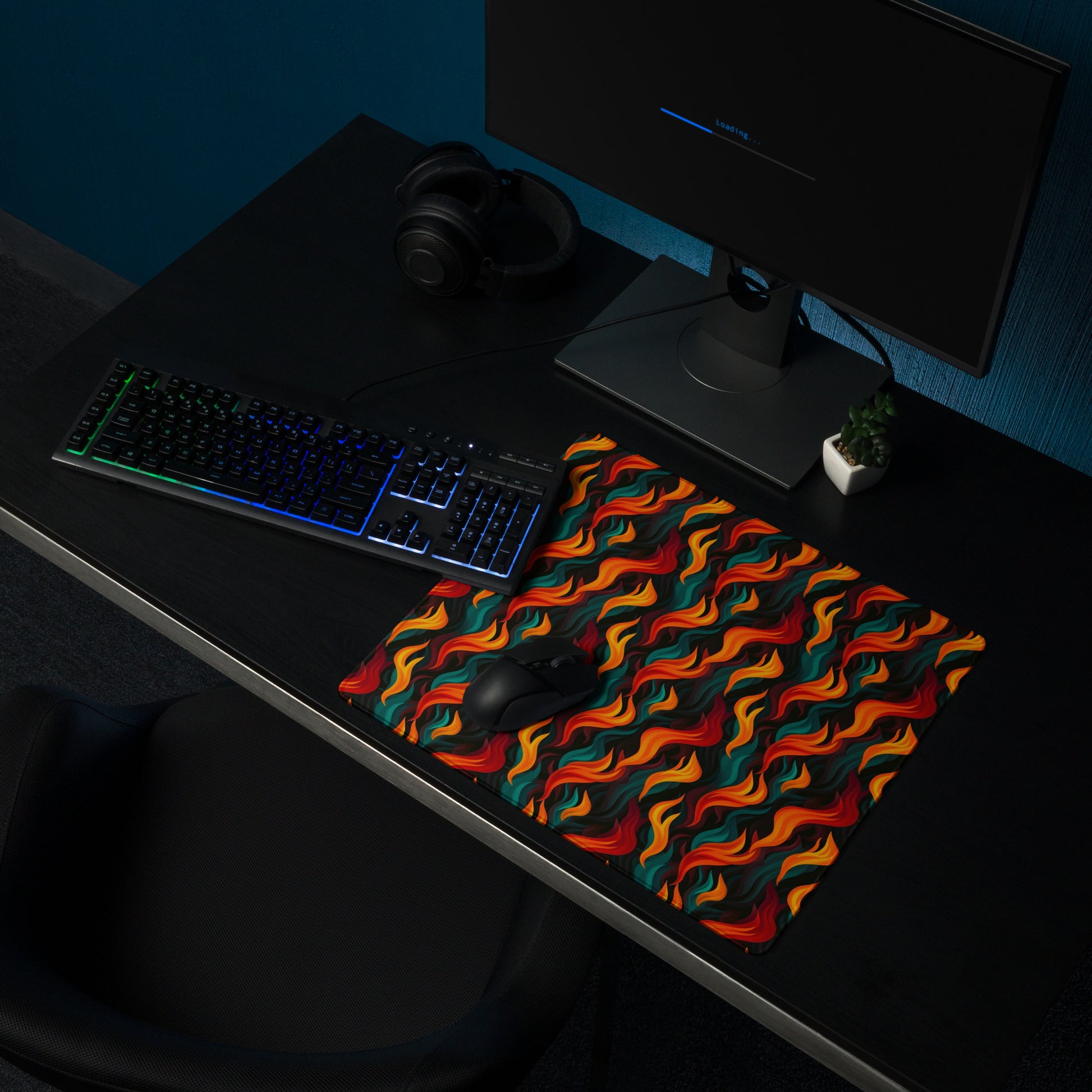 A 36" x 18" desk pad with a wavy flame pattern on it shown on a desk setup. Red and Teal in color.