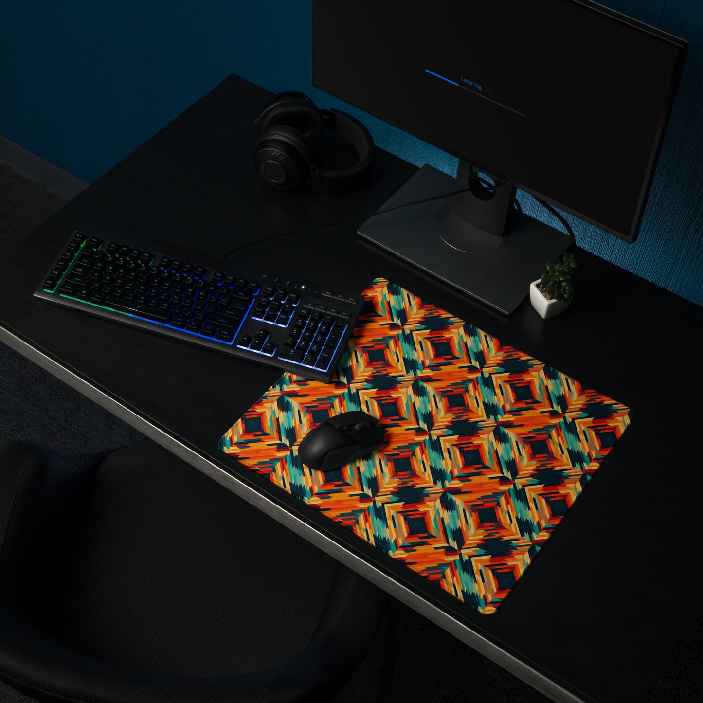 An 18" x 16" desk pad with a tiled abstract pattern on it shown on a desk setup. Orange in color.