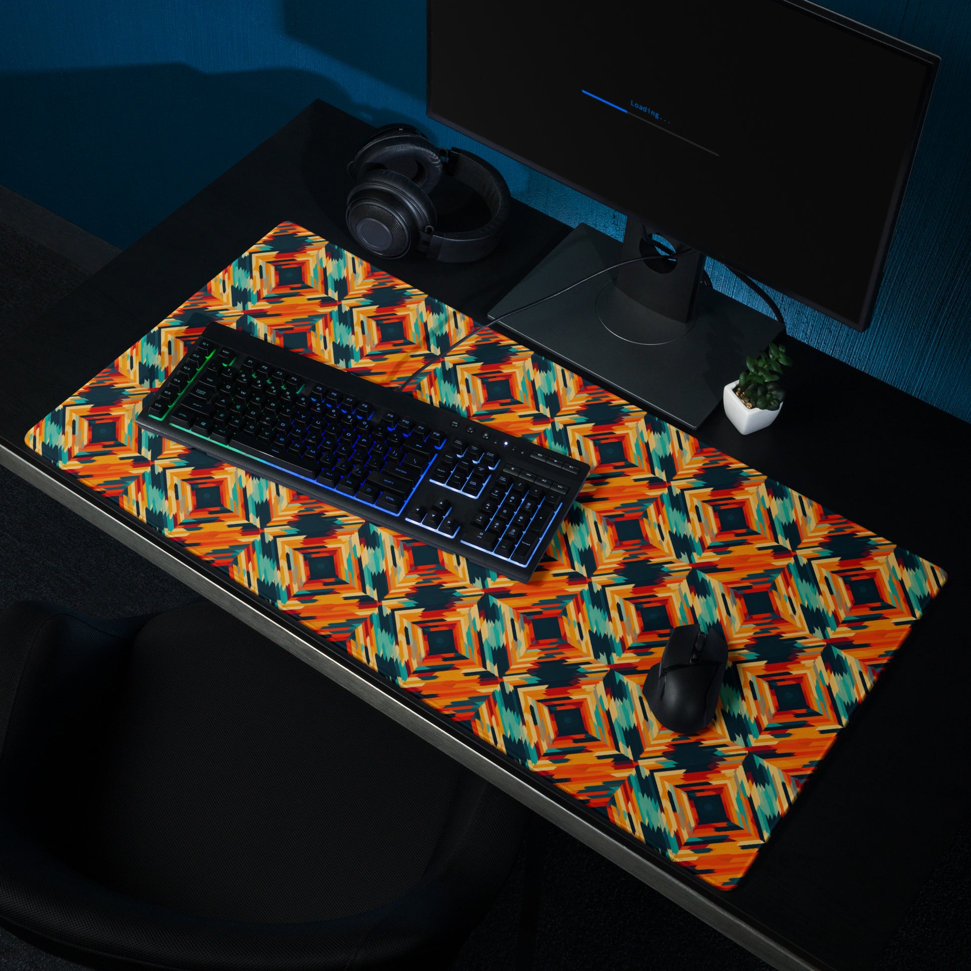 A 36" x 18" desk pad with a tiled abstract pattern on it shown on a desk setup. Orange in color.