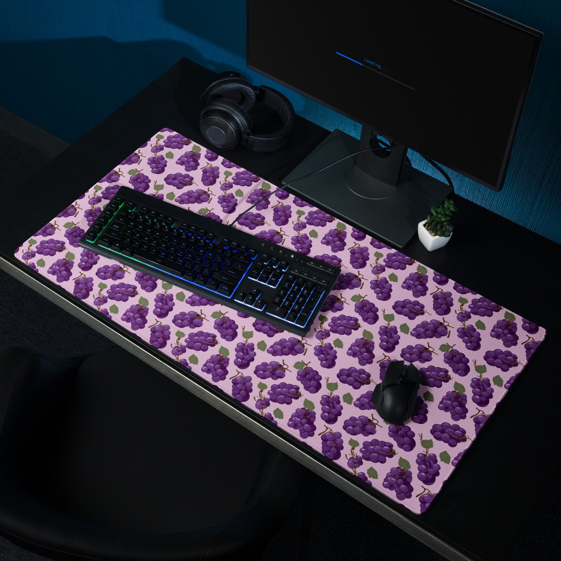 A 36" x 18" desk pad with bushels of grapes all over it shown on a desk setup. Purple in color.