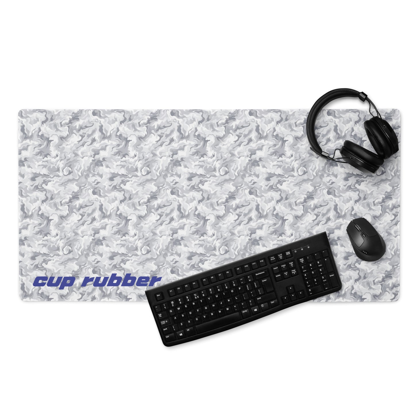 A 36" x 18" desk pad with a camo pattern and the word "Cup Rubber" on it in the bottom left corner displayed with a keyboard, headphones and a mouse. Beige and White in color.