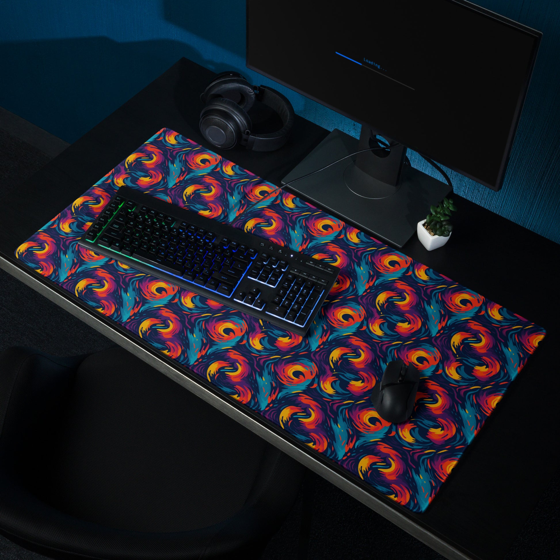 A 36" x 18" desk pad with fiery swirls on it shown on a desk setup. Red and Blue in color.