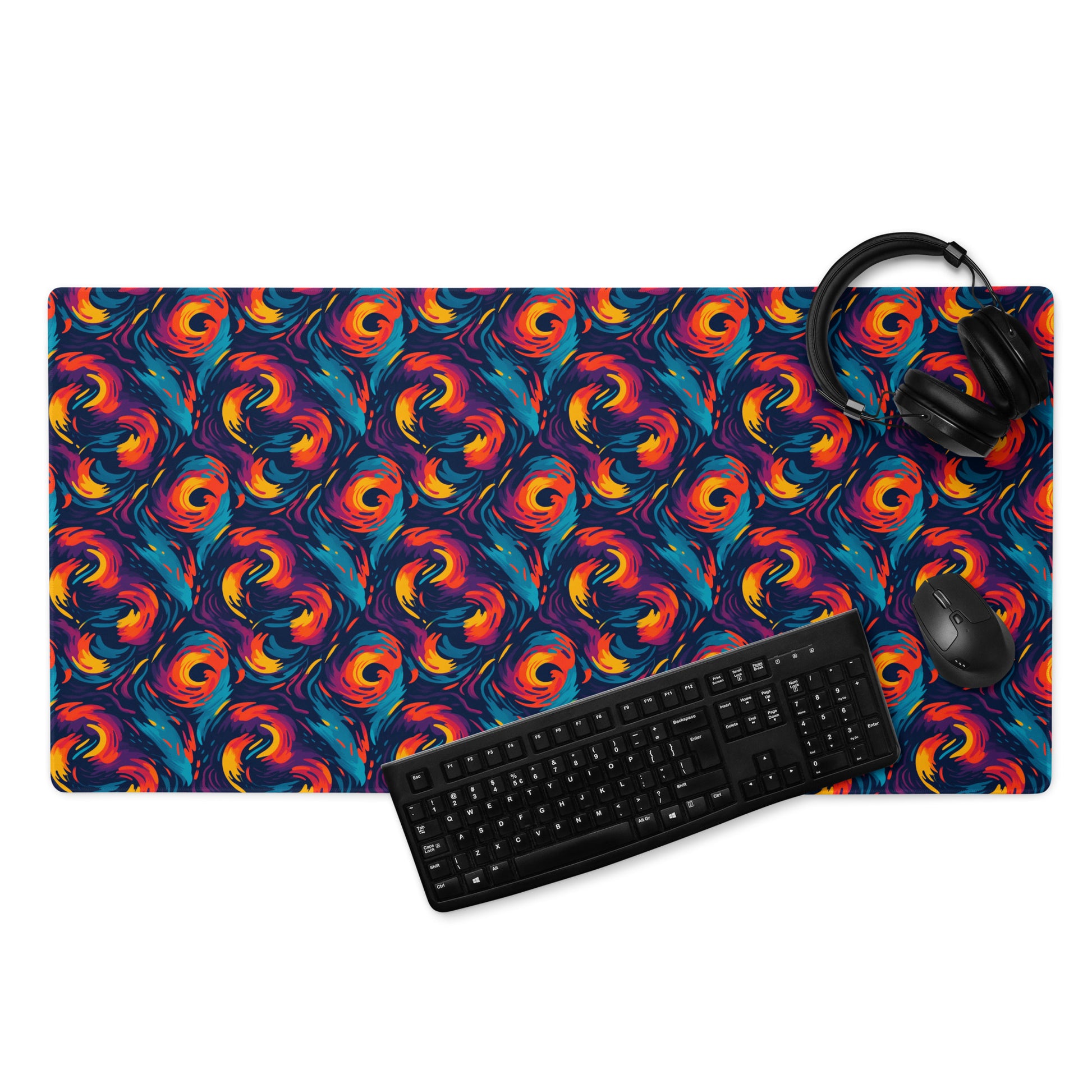 A 36" x 18" desk pad with fiery swirls on it displayed with a keyboard, headphones and a mouse. Red and Blue in color.