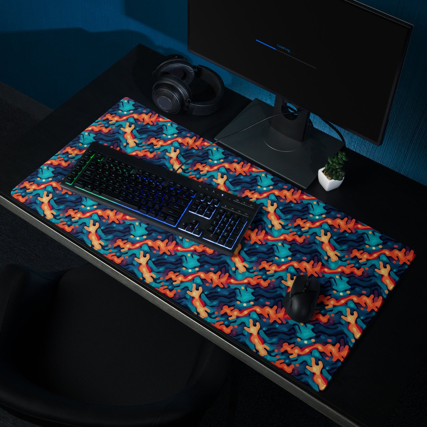 A 36" x 18" desk pad with a wavy woven pattern on it shown on a desk setup. Red and Blue in color.