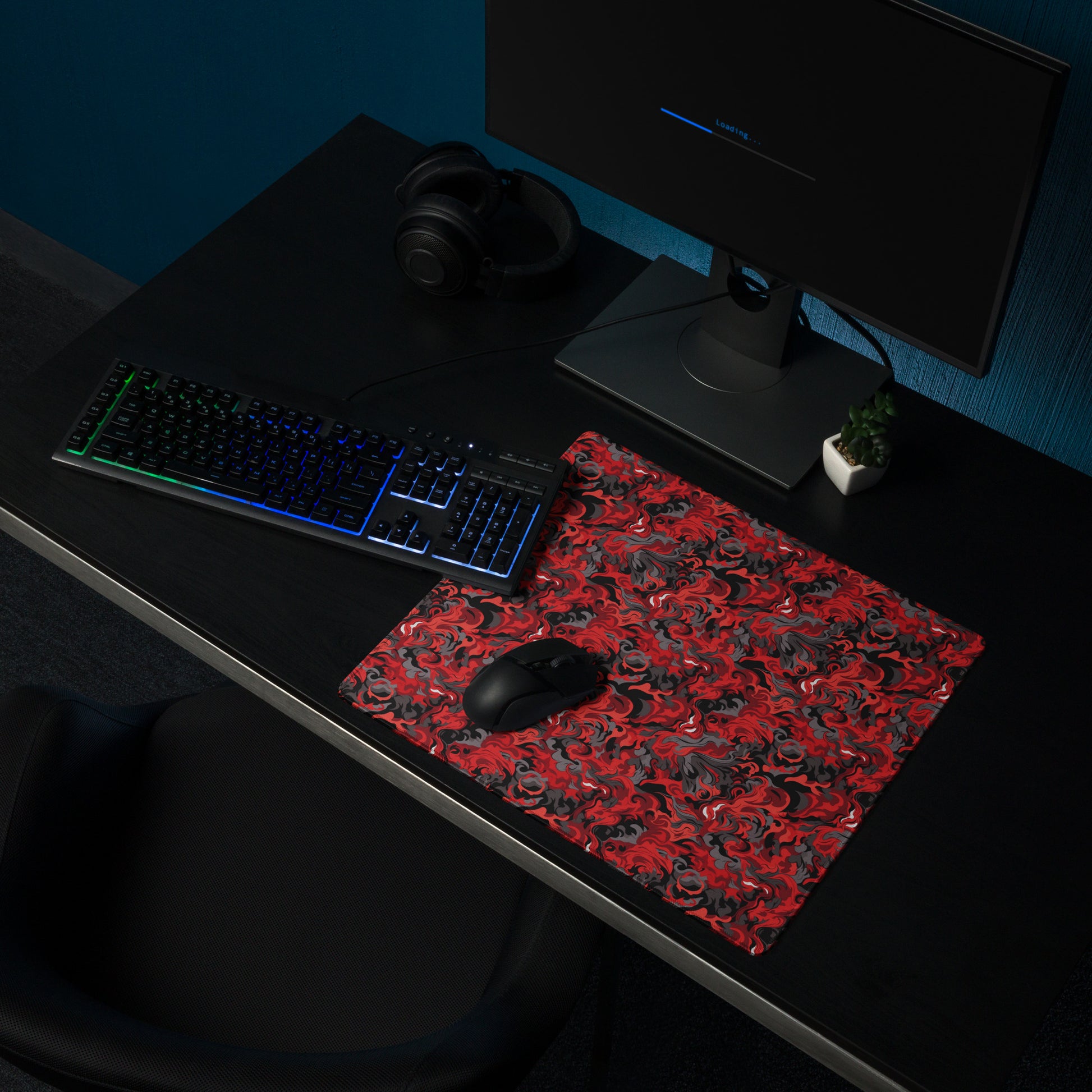 A 18" x 16" desk pad with a black and red camo pattern sitting on a desk.