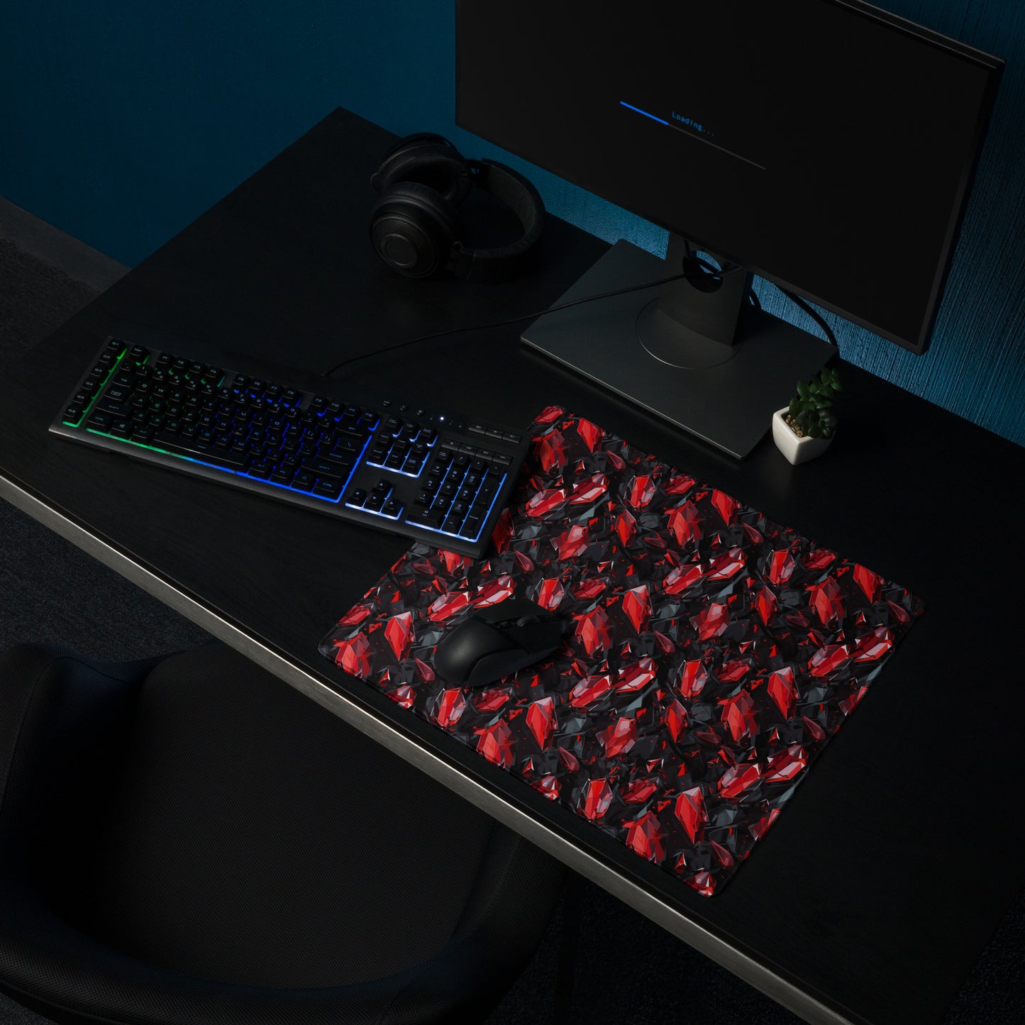 An 18" x 16" gaming desk pad with black and red crystals. It sits on a black desk with a keyboard, monitor, and mouse.