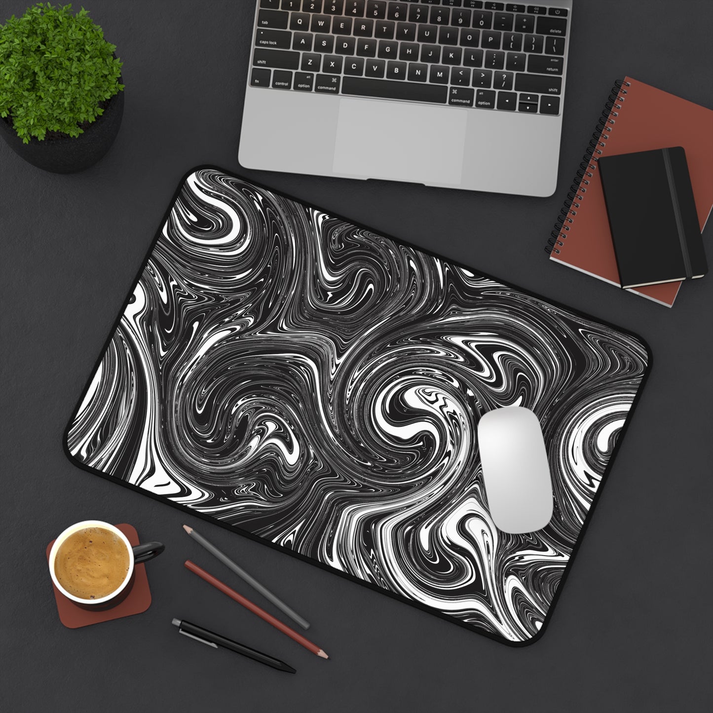 A 12" x 18" desk mat with black and white swirls sitting at an angle.